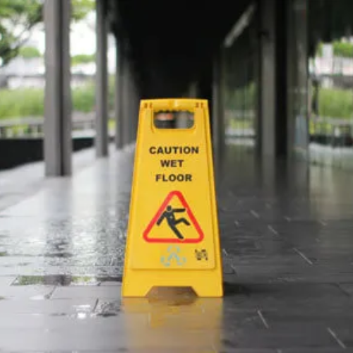 A yellow caution wet floor sign is sitting on the sidewalk.