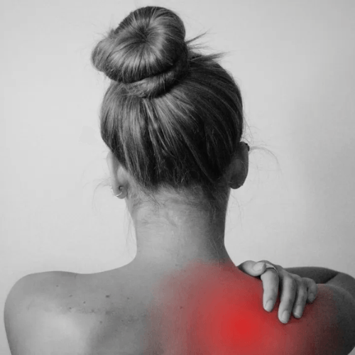 A woman is holding her shoulder in pain.