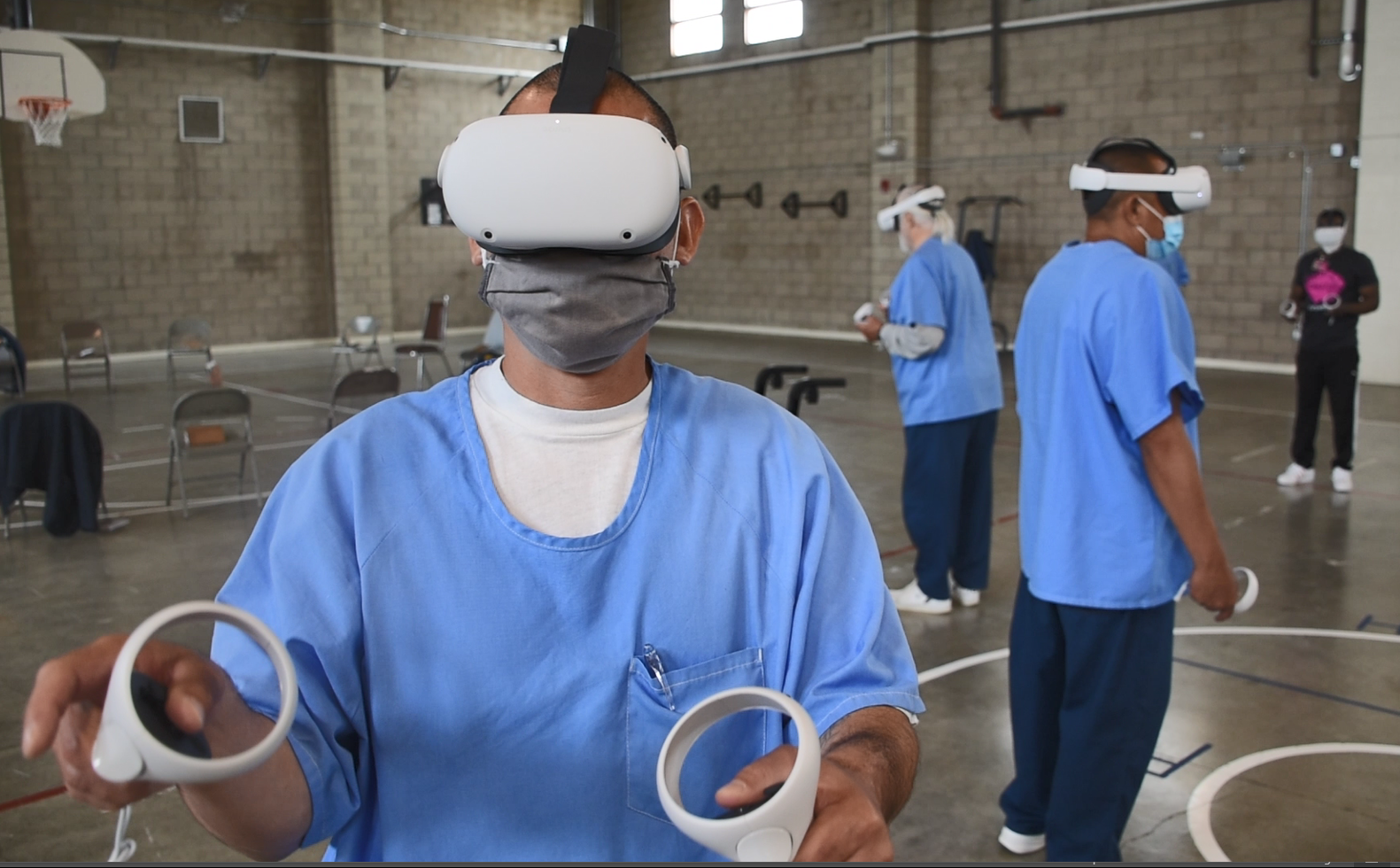 A man wearing a virtual reality headset is holding two controllers.