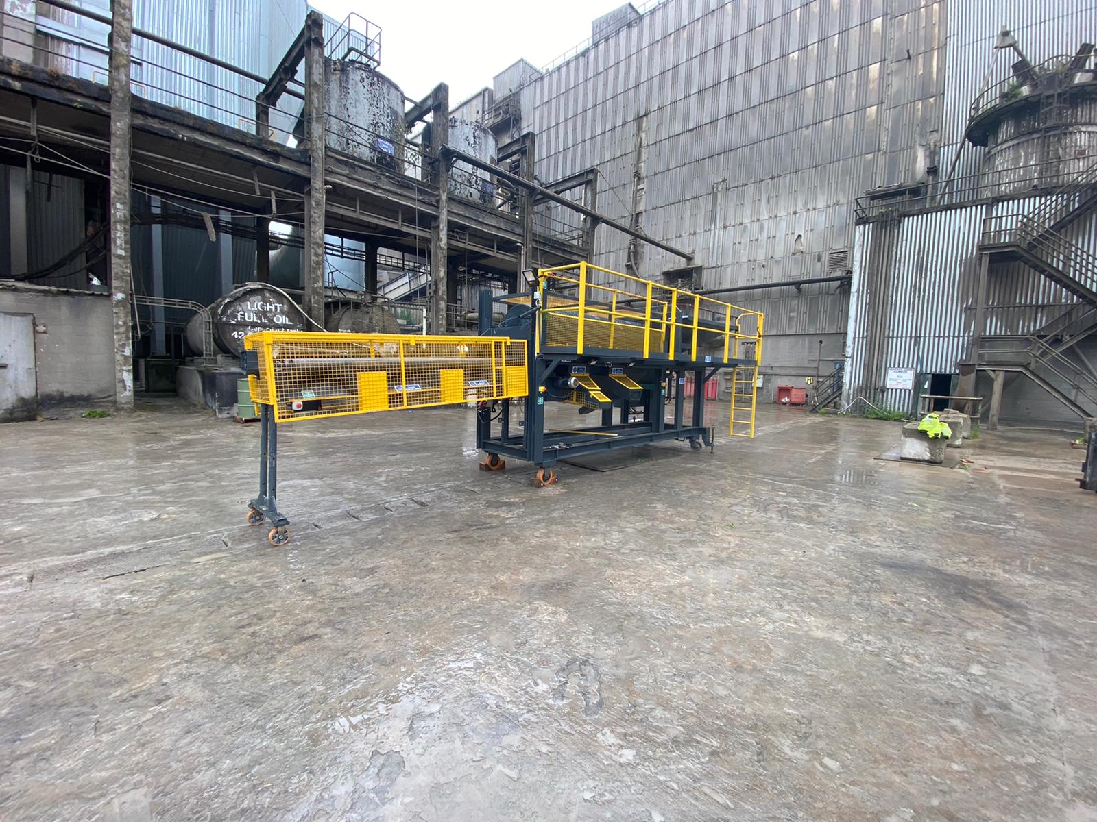 A yellow machine is sitting in a parking lot in front of a building.