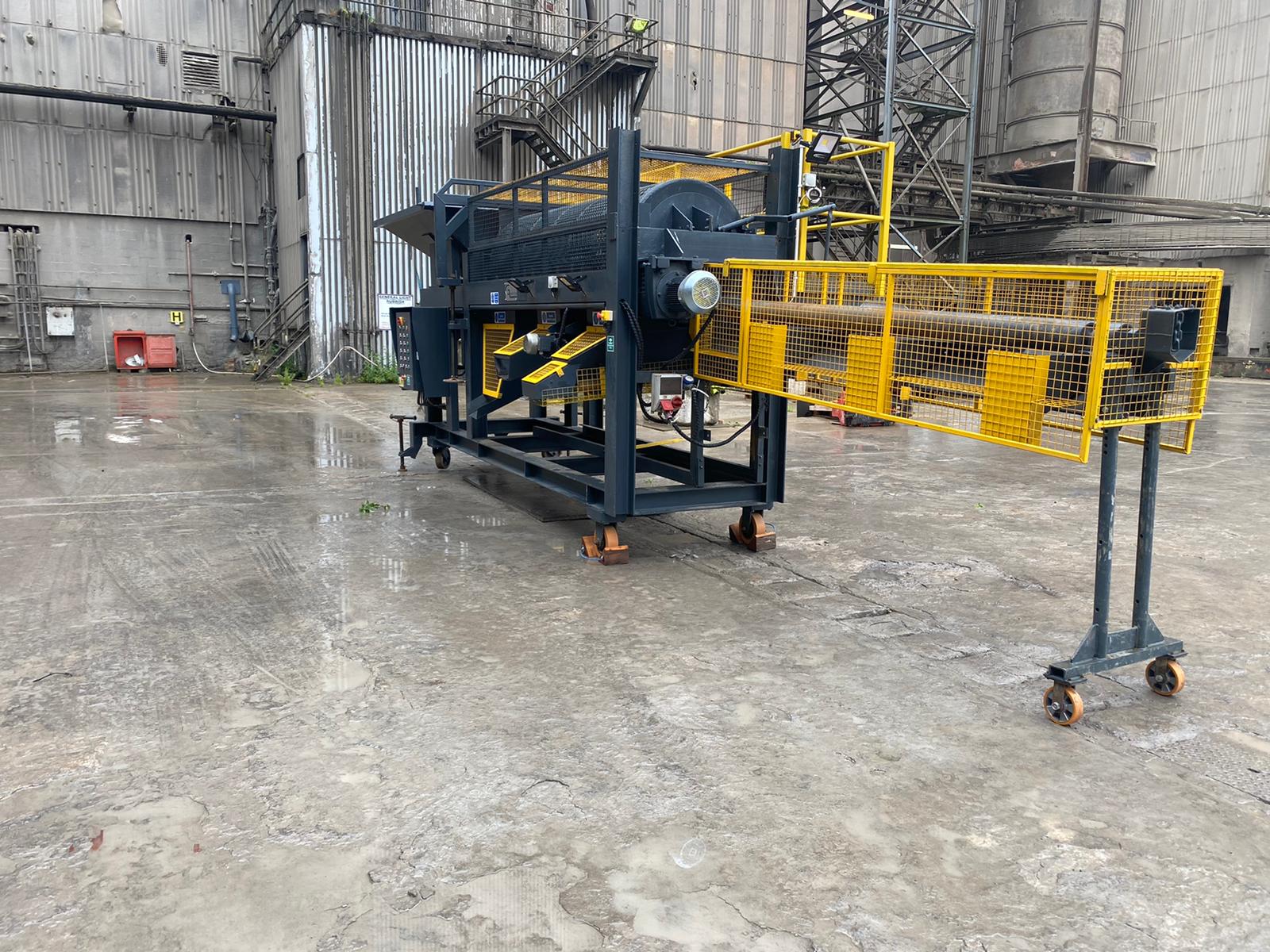 A machine is sitting on a cart in a parking lot in front of a building.