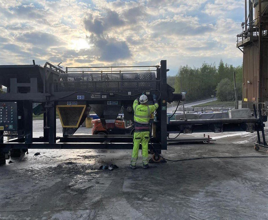 A man is working on a machine in a parking lot.