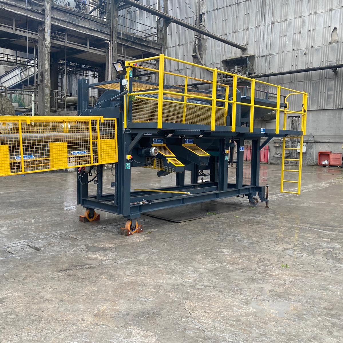 A machine with a yellow railing is sitting in a warehouse.
