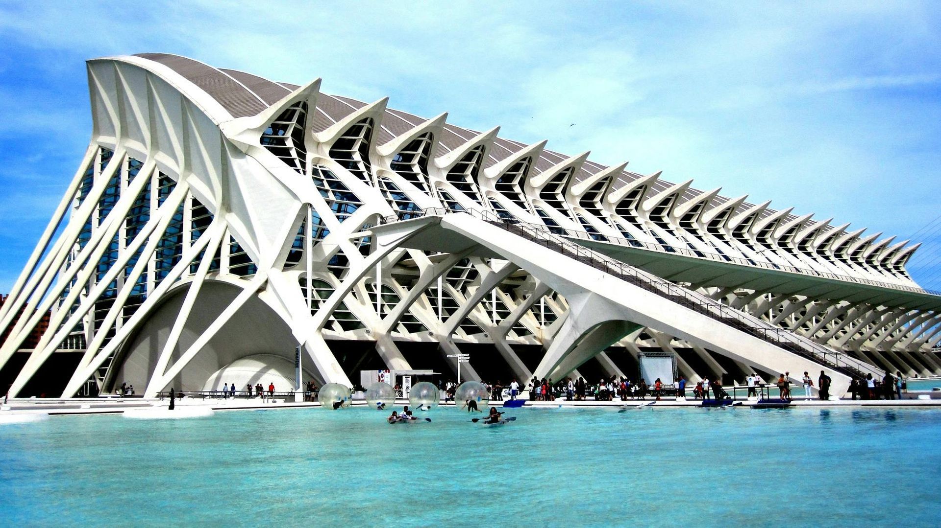 The white, rib-like structure of the Museo de las Ciencias Príncipe Felipe in Valencia, Spain, reflecting in blue water.
