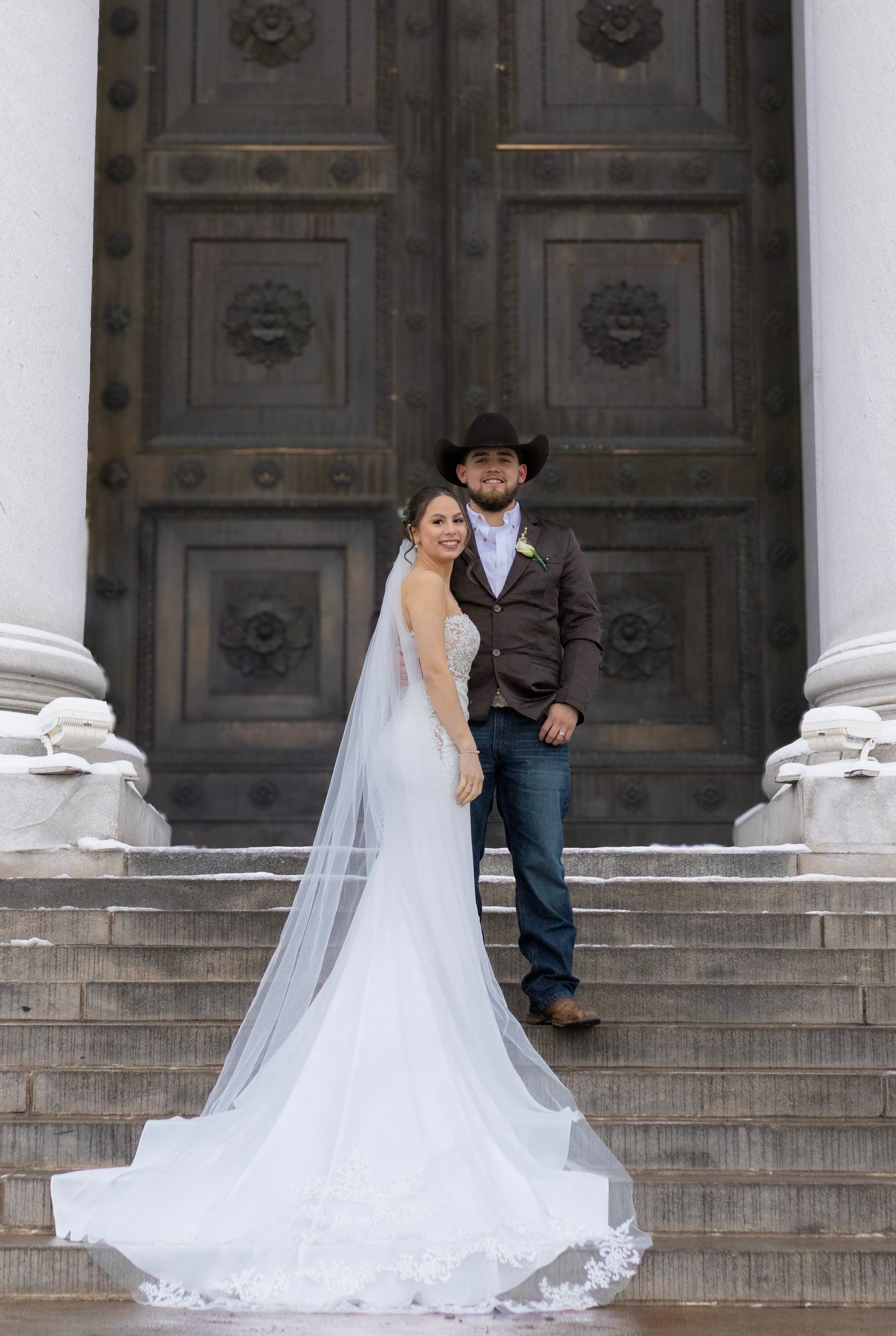 A bride and groom are posing for a picture on the steps of a building.