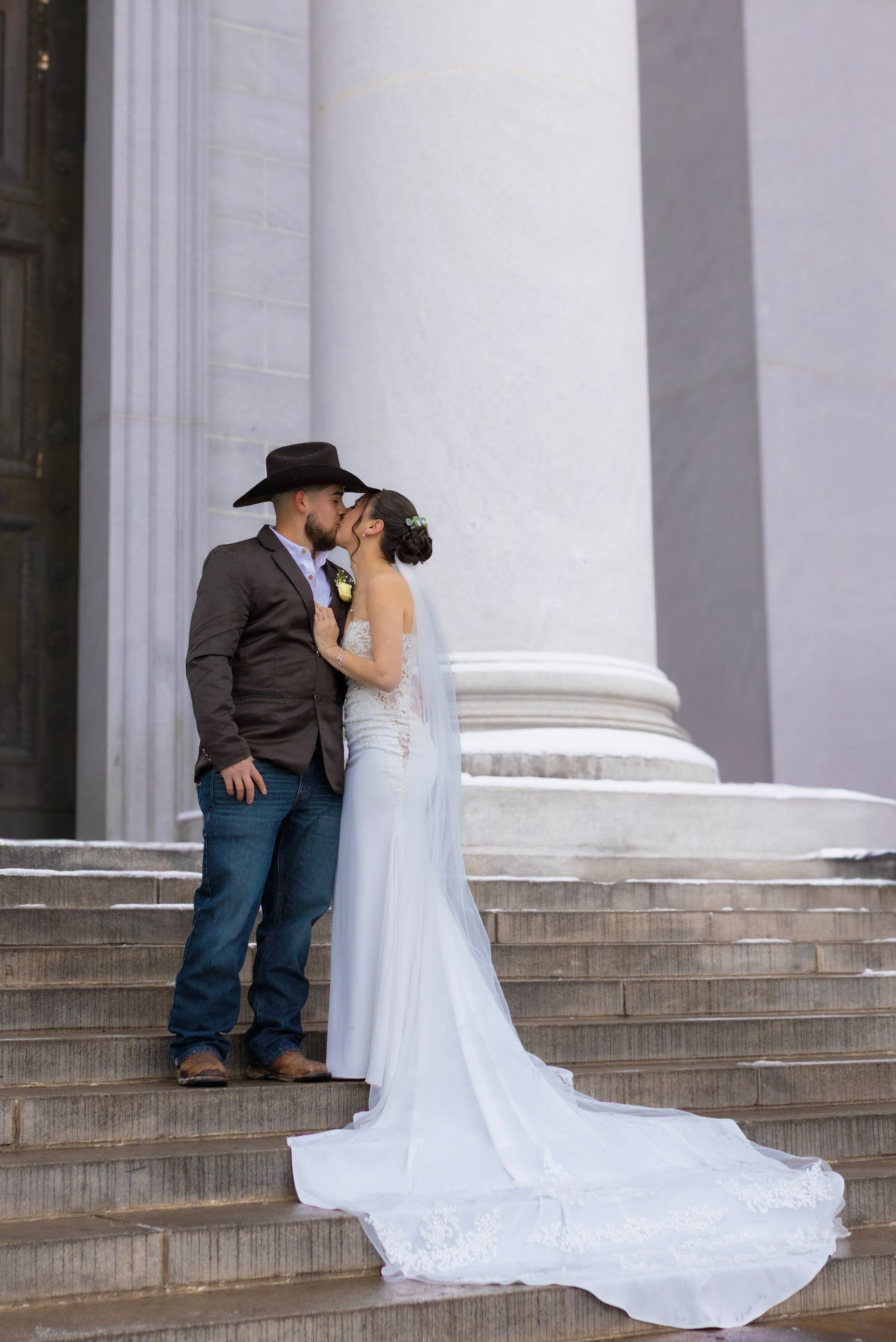 A bride and groom are kissing on the steps of a building.
