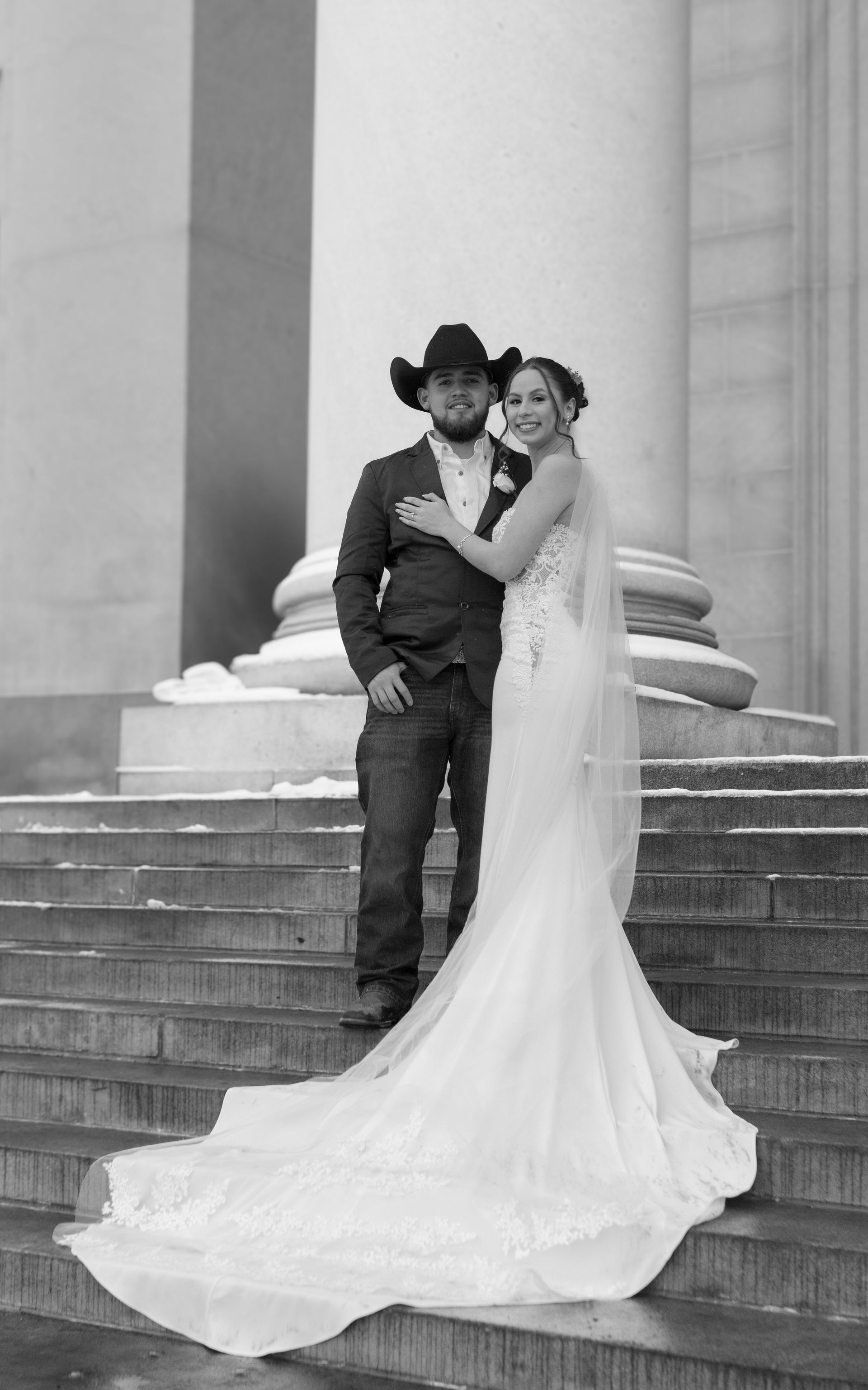 A bride and groom are posing for a picture on a set of stairs.