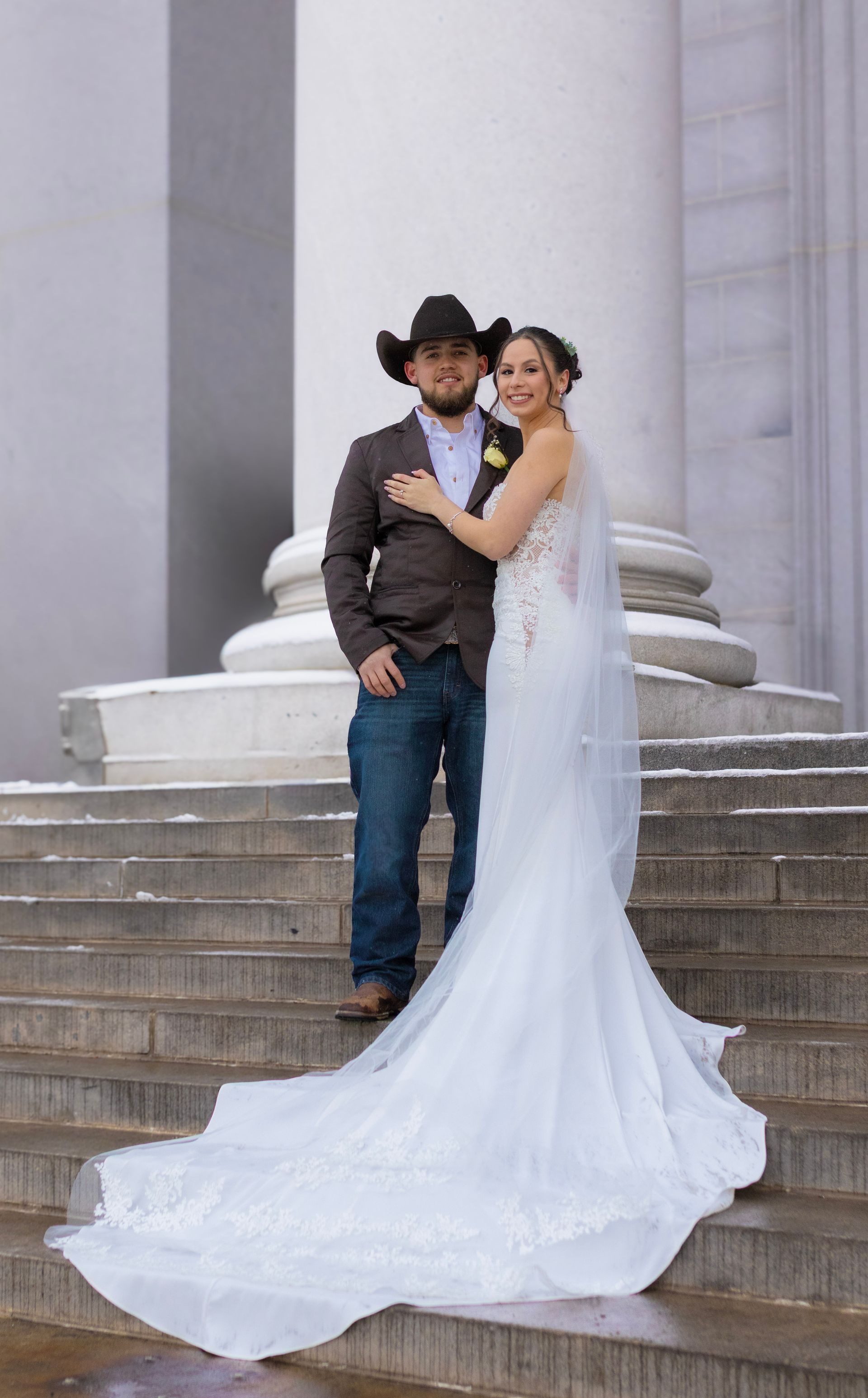 A bride and groom are posing for a picture on the steps of a building.