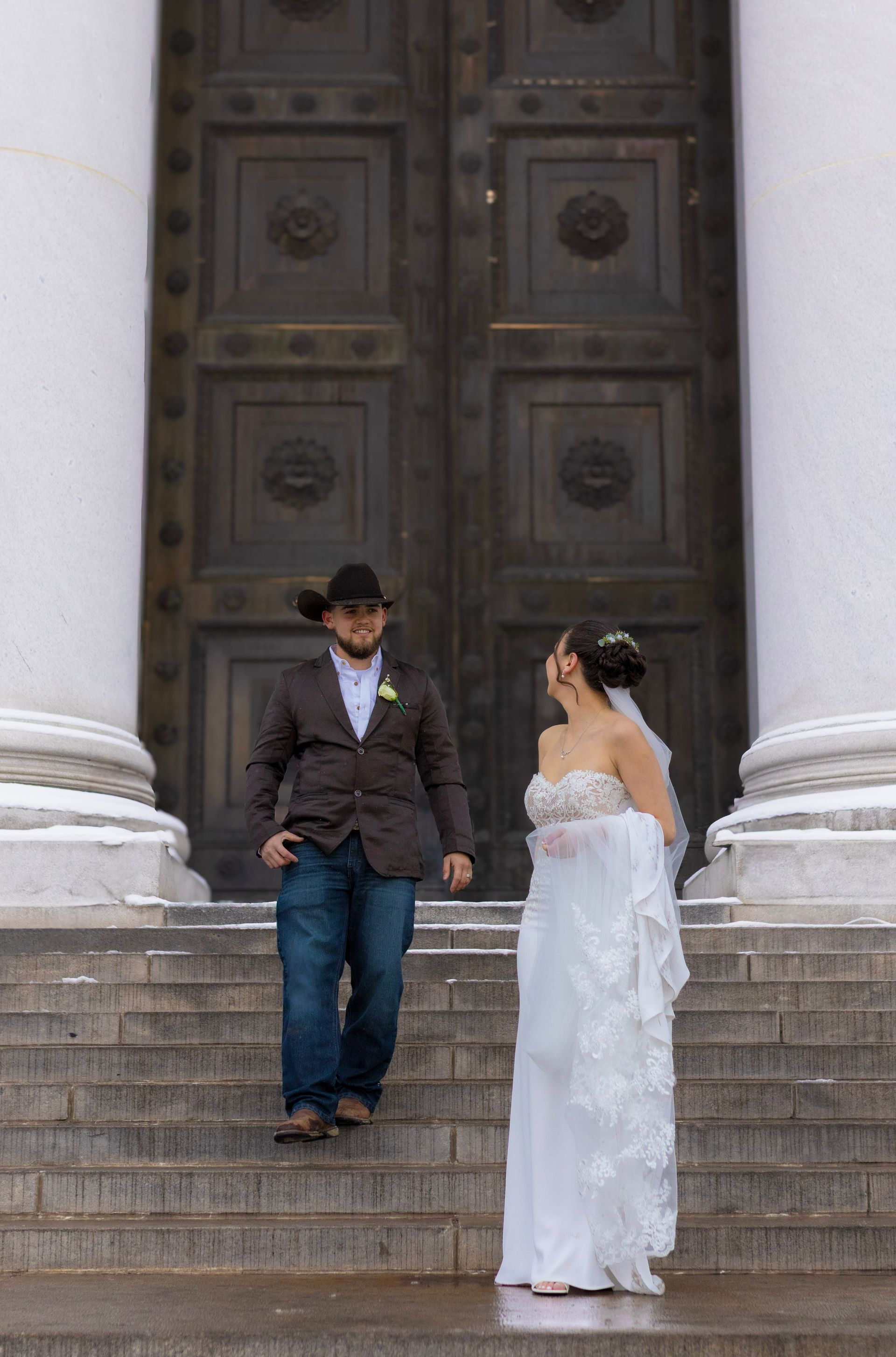 A bride and groom are standing on the steps of a building.