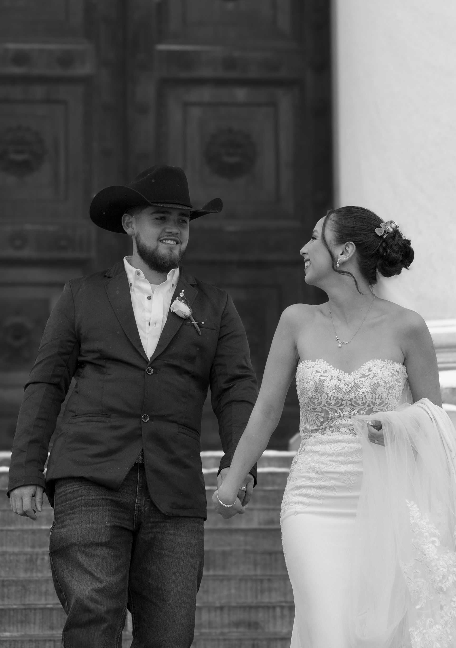A black and white photo of a bride and groom holding hands.