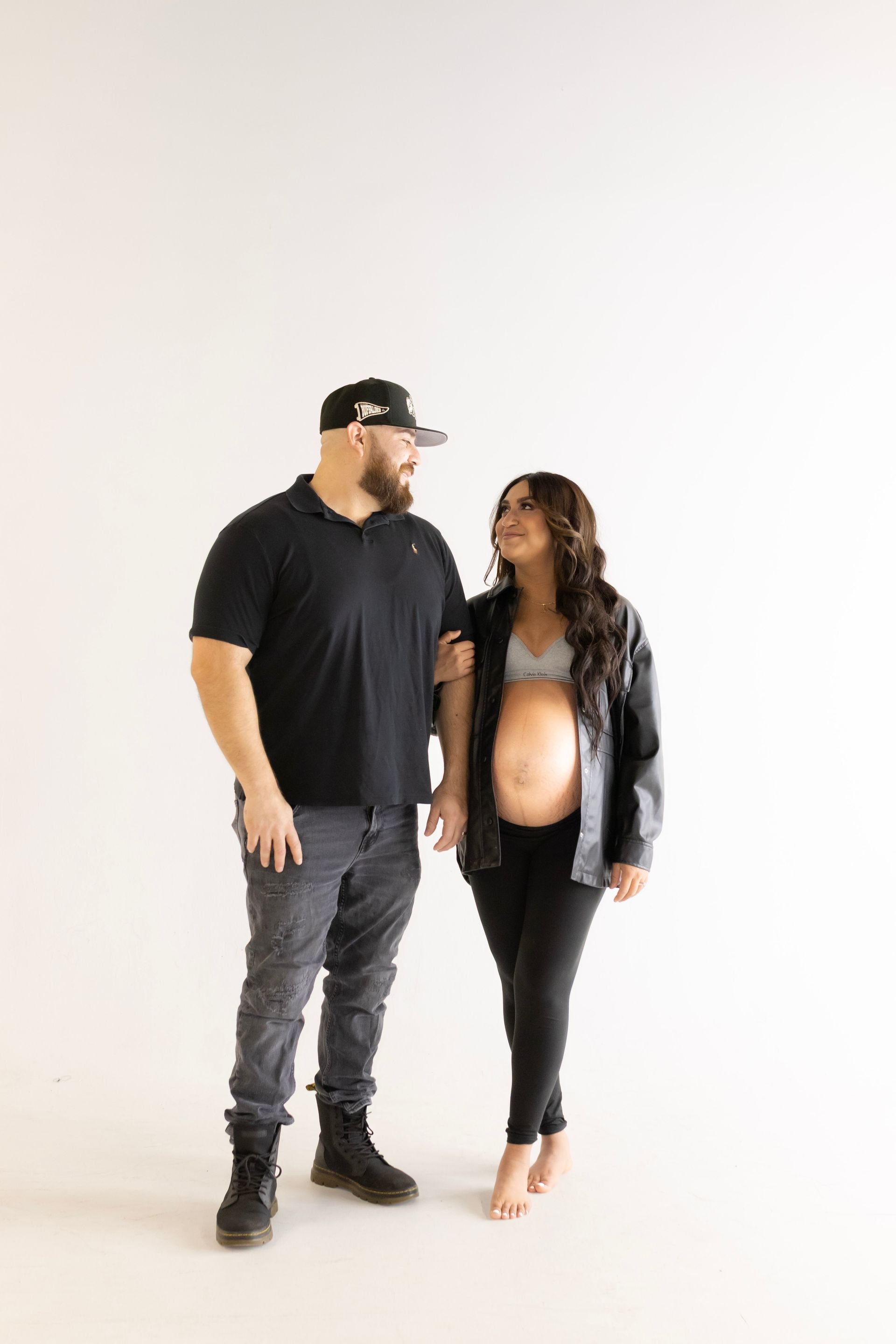 A man and a pregnant woman are standing next to each other and holding hands.