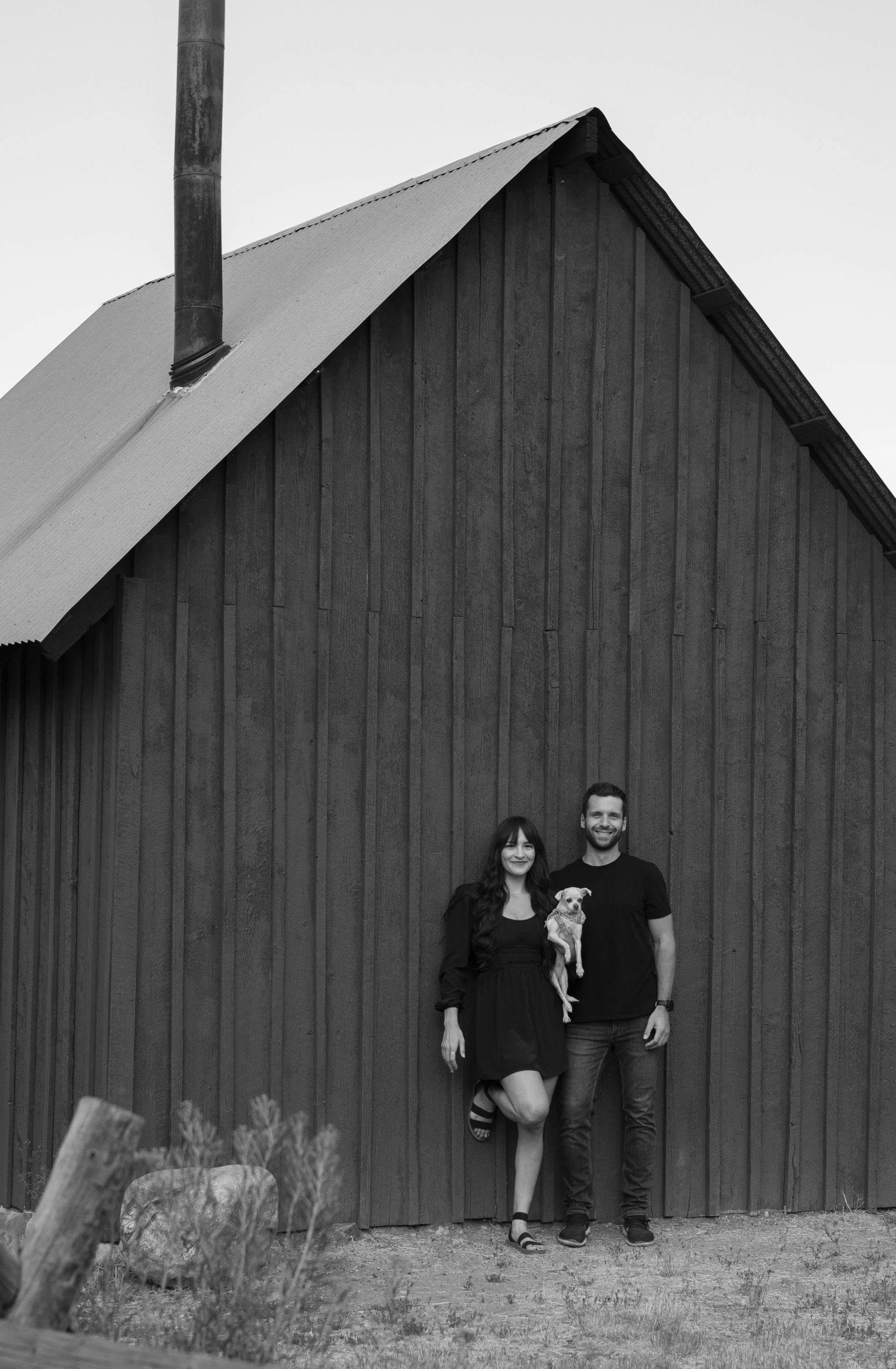 A man and a woman are standing in front of a wooden building.