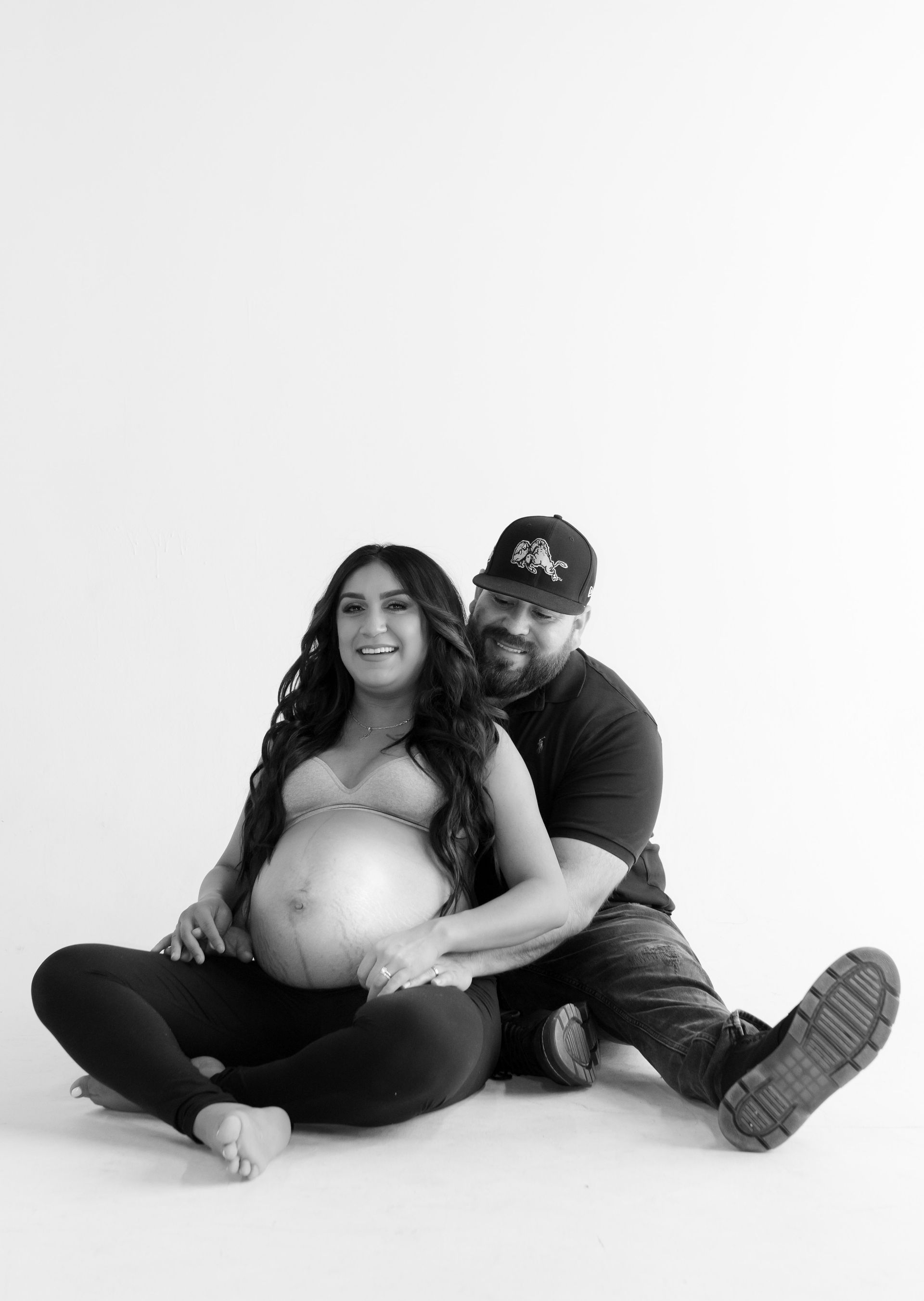 A man and a pregnant woman are sitting on the floor.