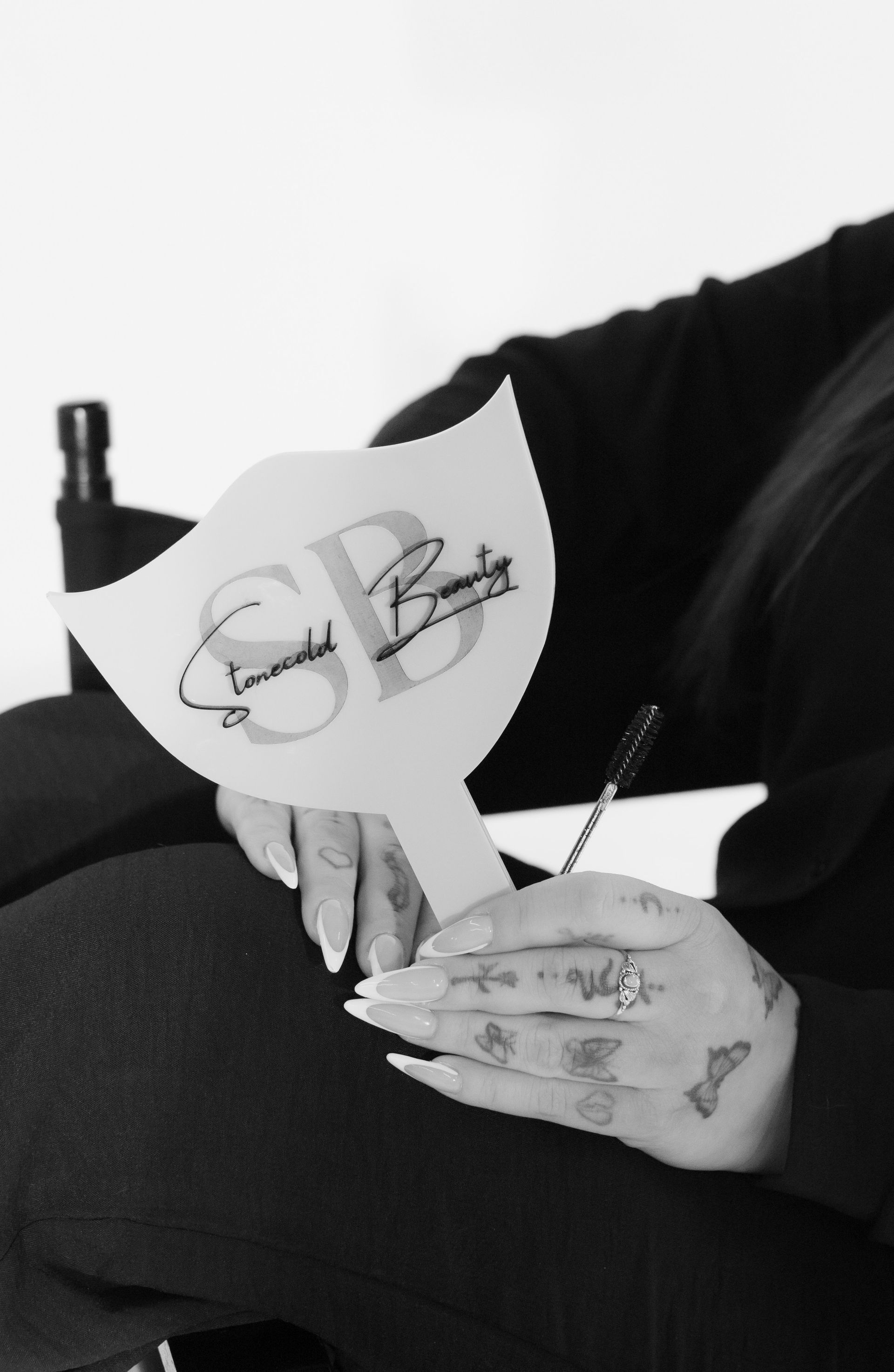A woman is holding a hand mirror with the letter sb on it