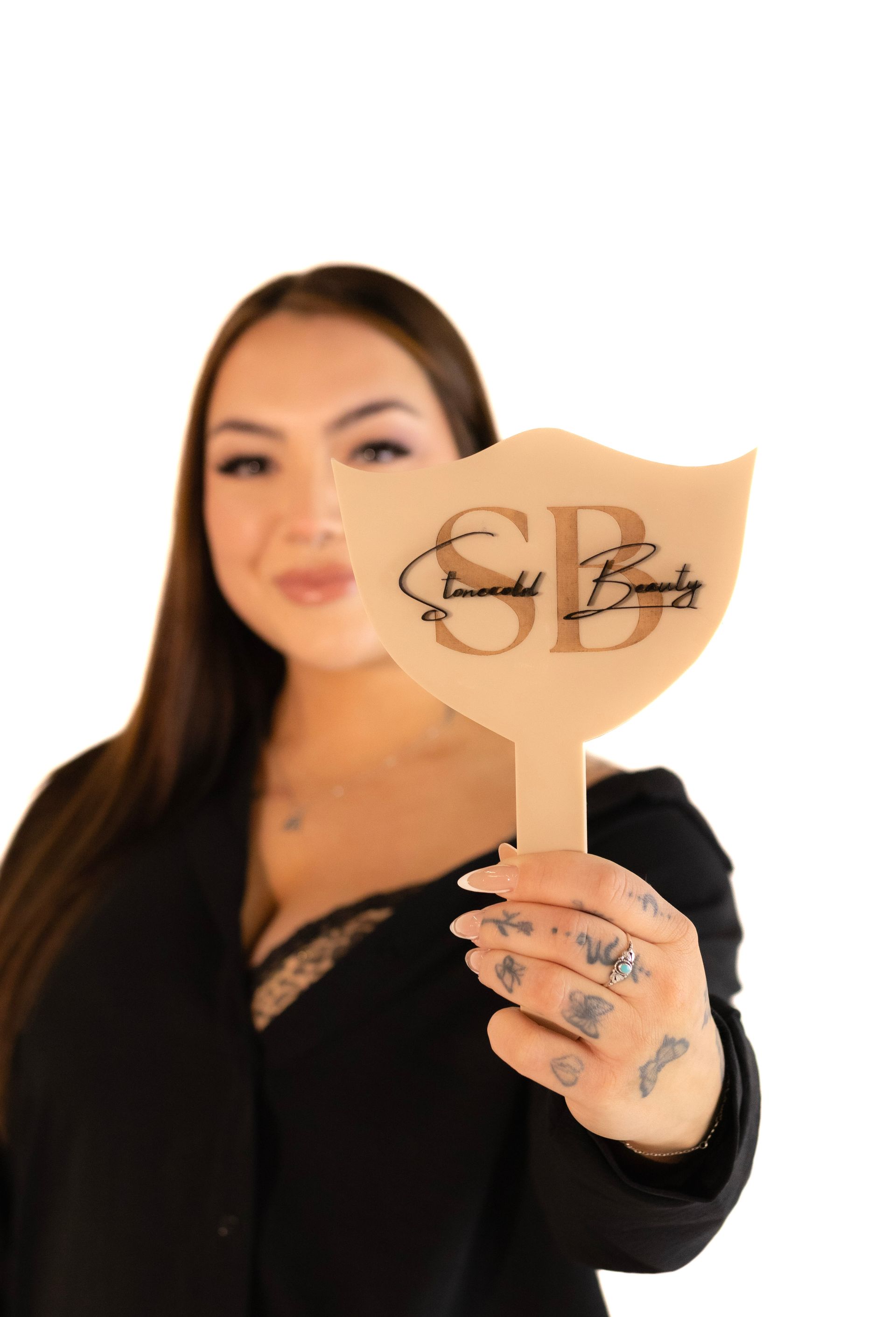 A woman is holding a hand mirror with the letter sb on it.