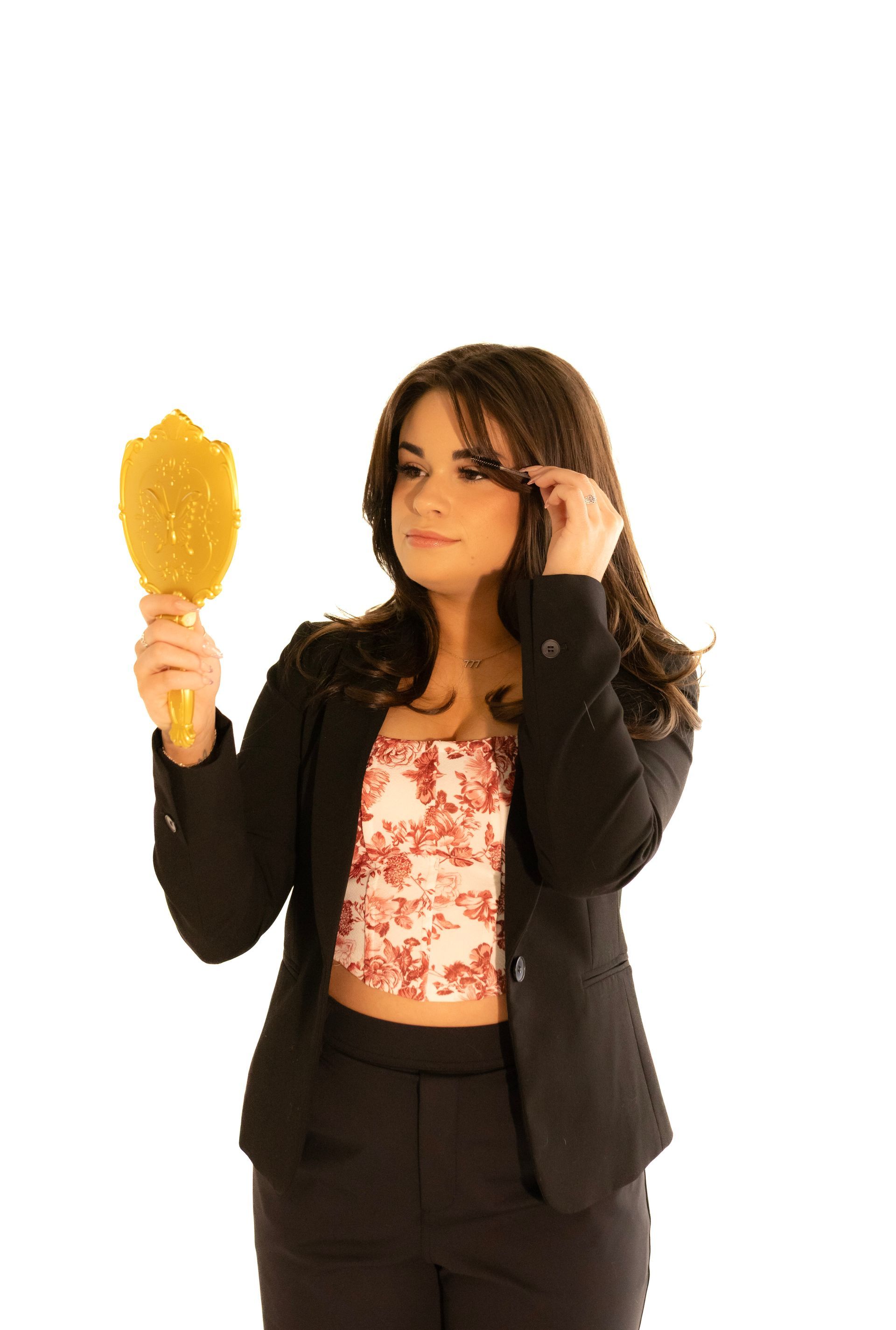 A woman in a suit is brushing her hair in front of a mirror.