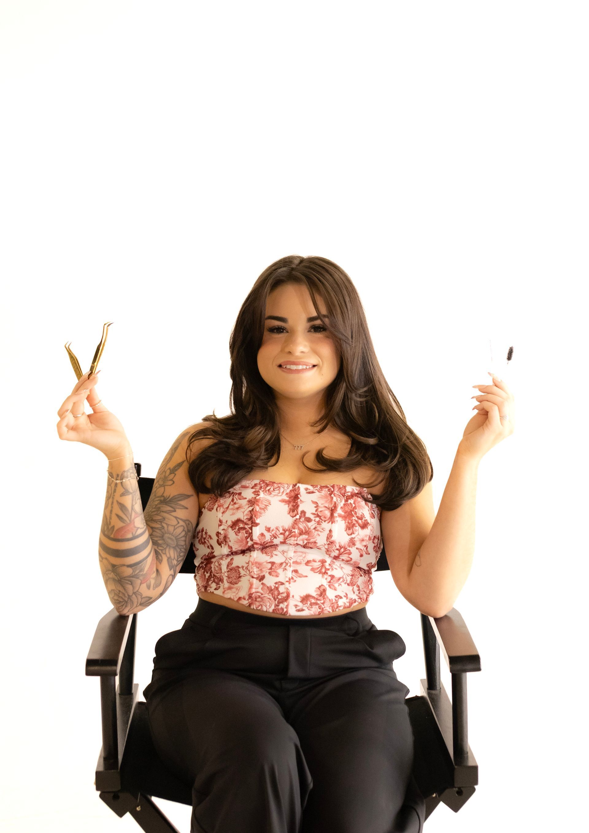 A woman is sitting in a chair holding a pair of scissors.