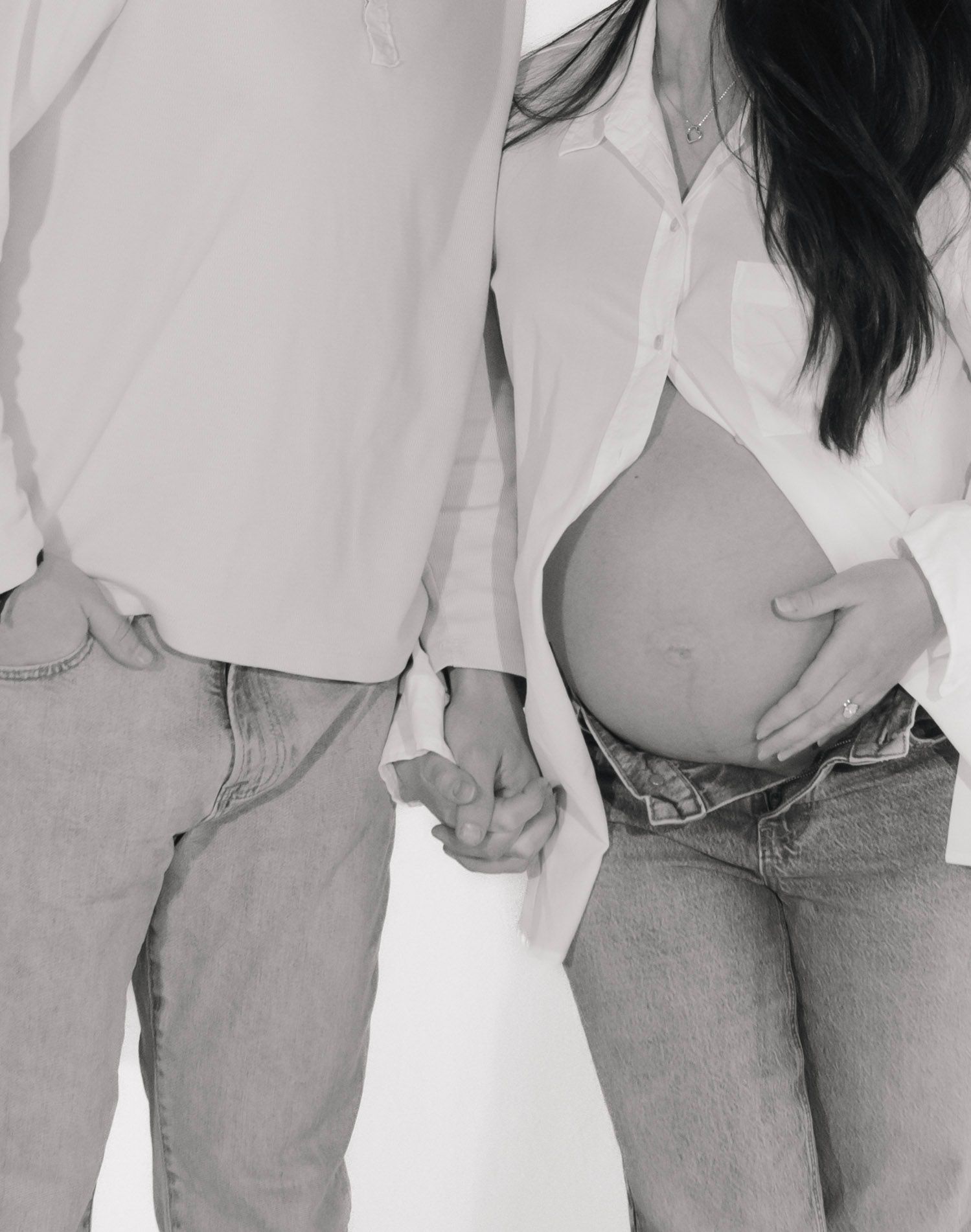 A man and a pregnant woman holding hands in a black and white photo