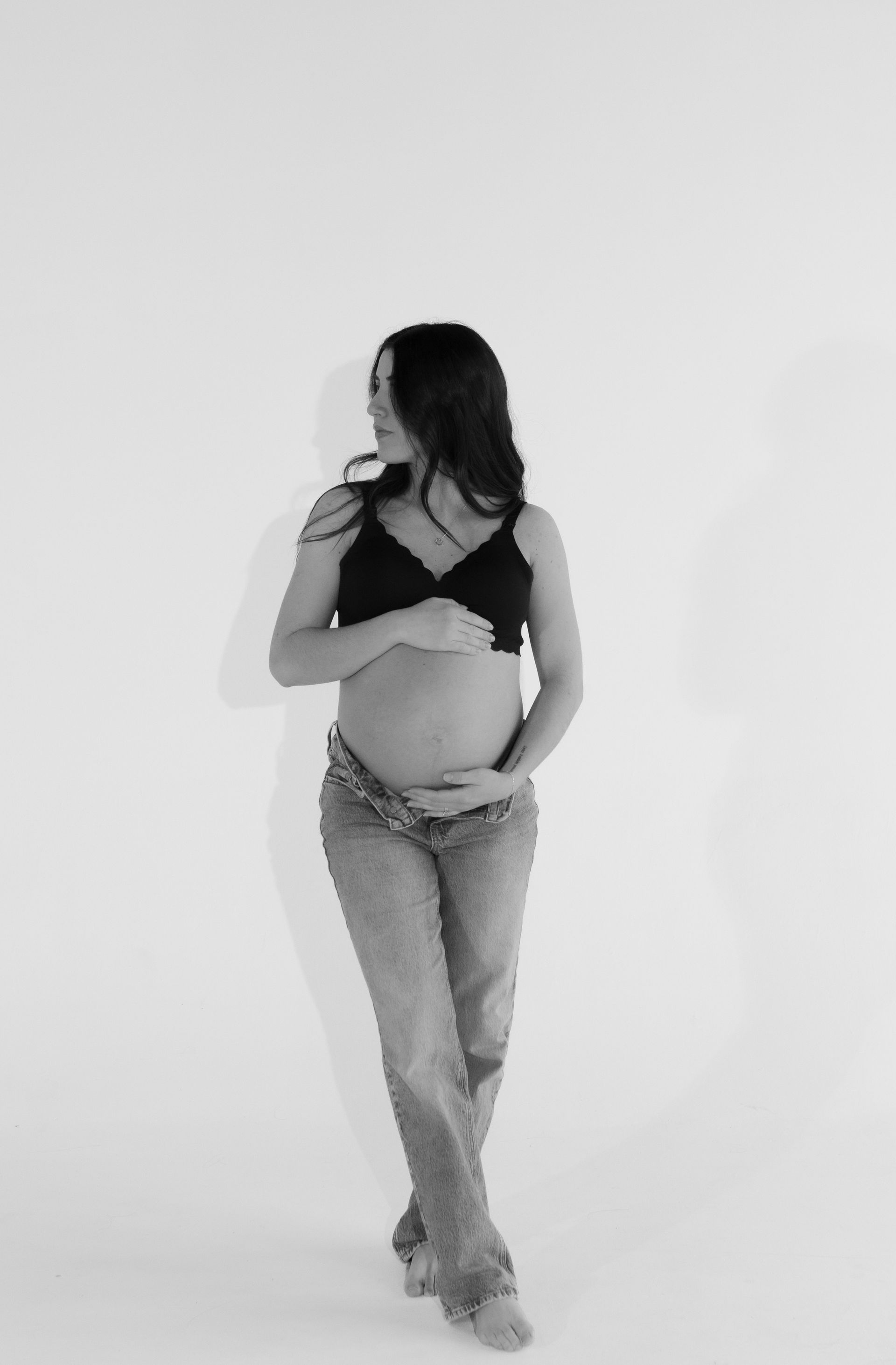 A black and white photo of a pregnant woman holding her belly.