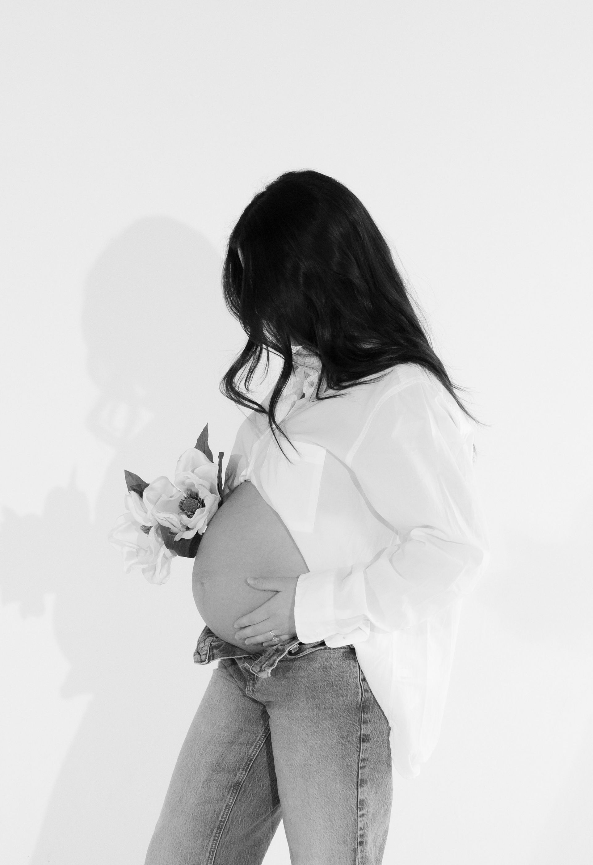 A black and white photo of a pregnant woman holding flowers.