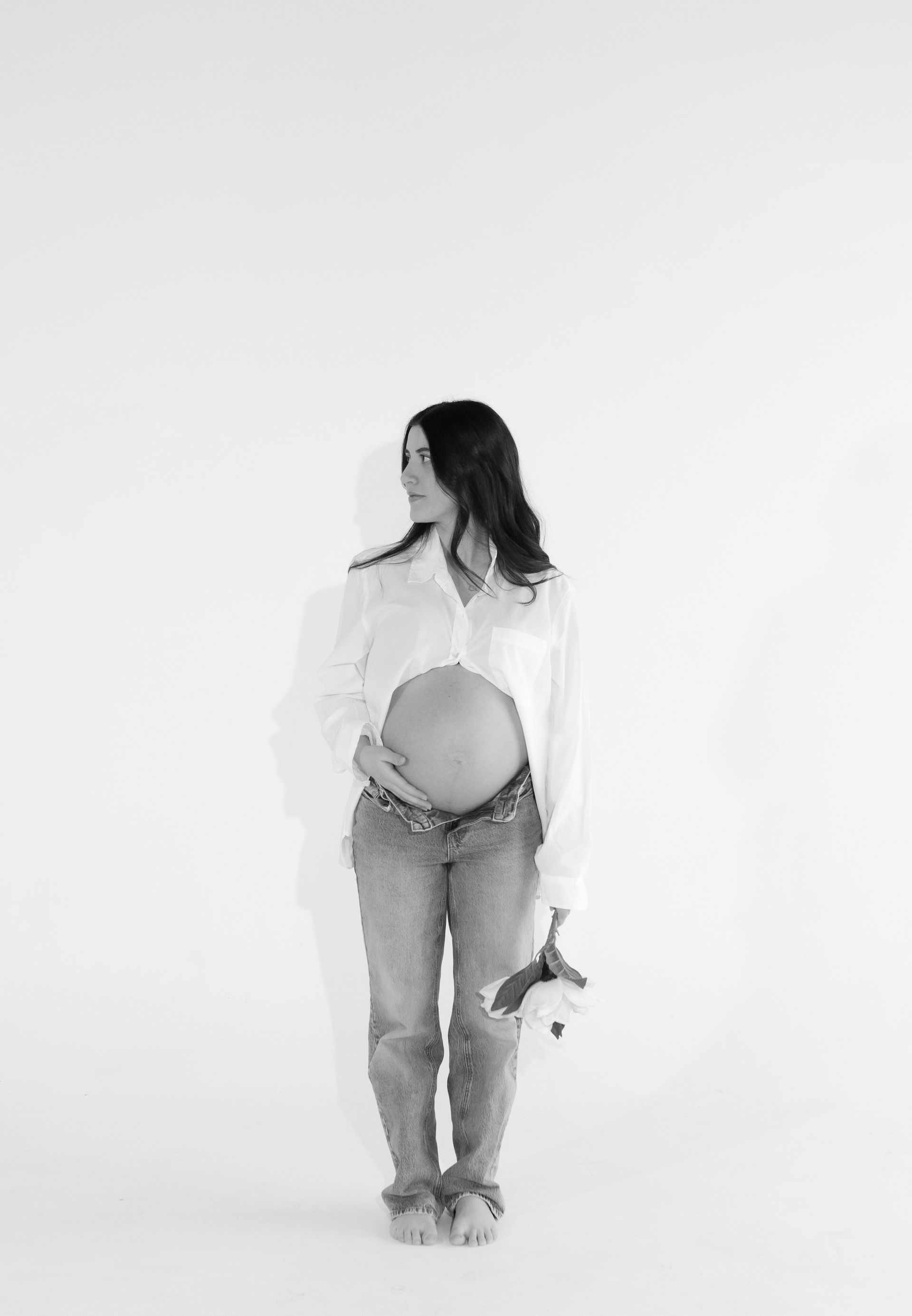 A black and white photo of a pregnant woman holding her belly.
