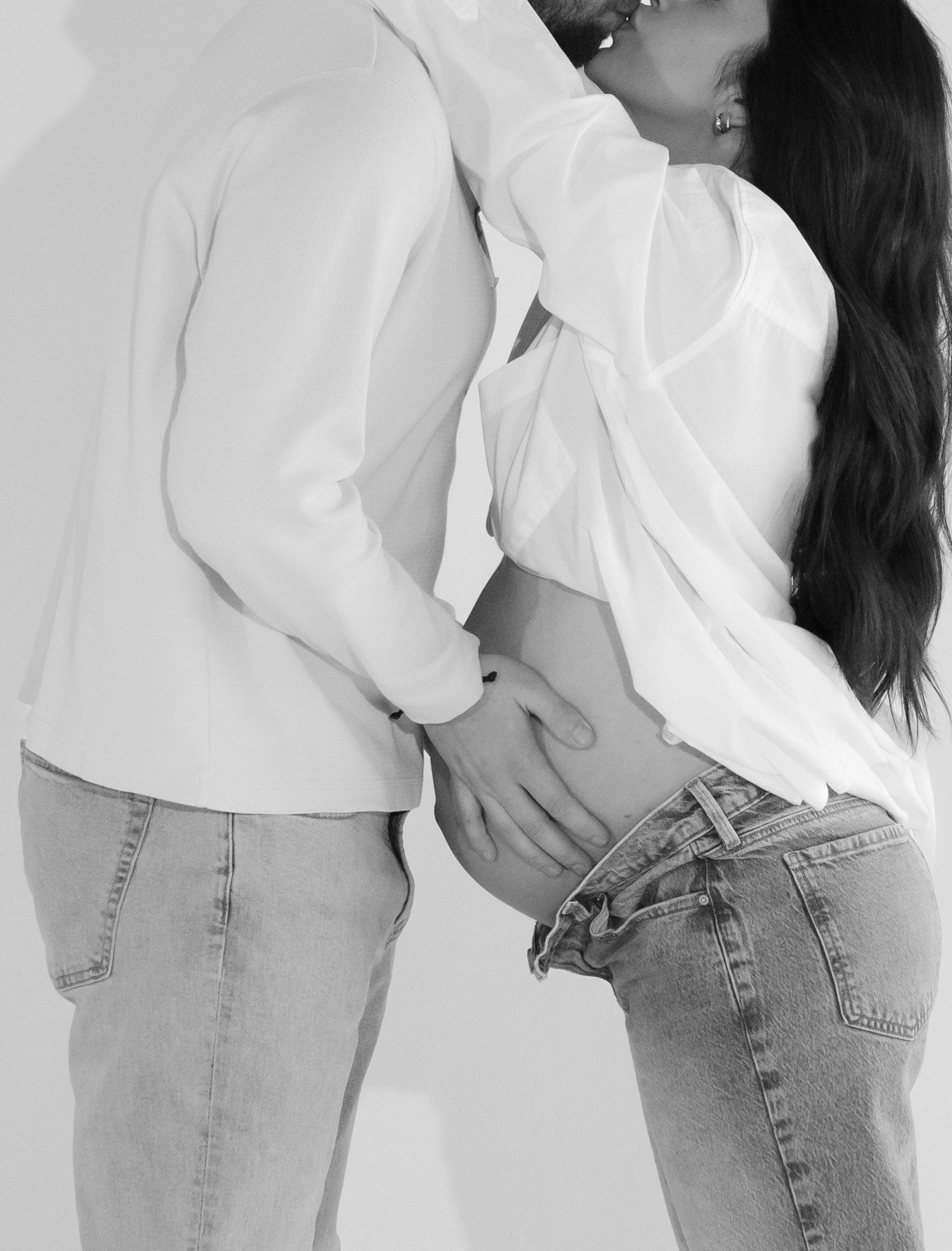 A man kissing a pregnant woman 's belly in a black and white photo