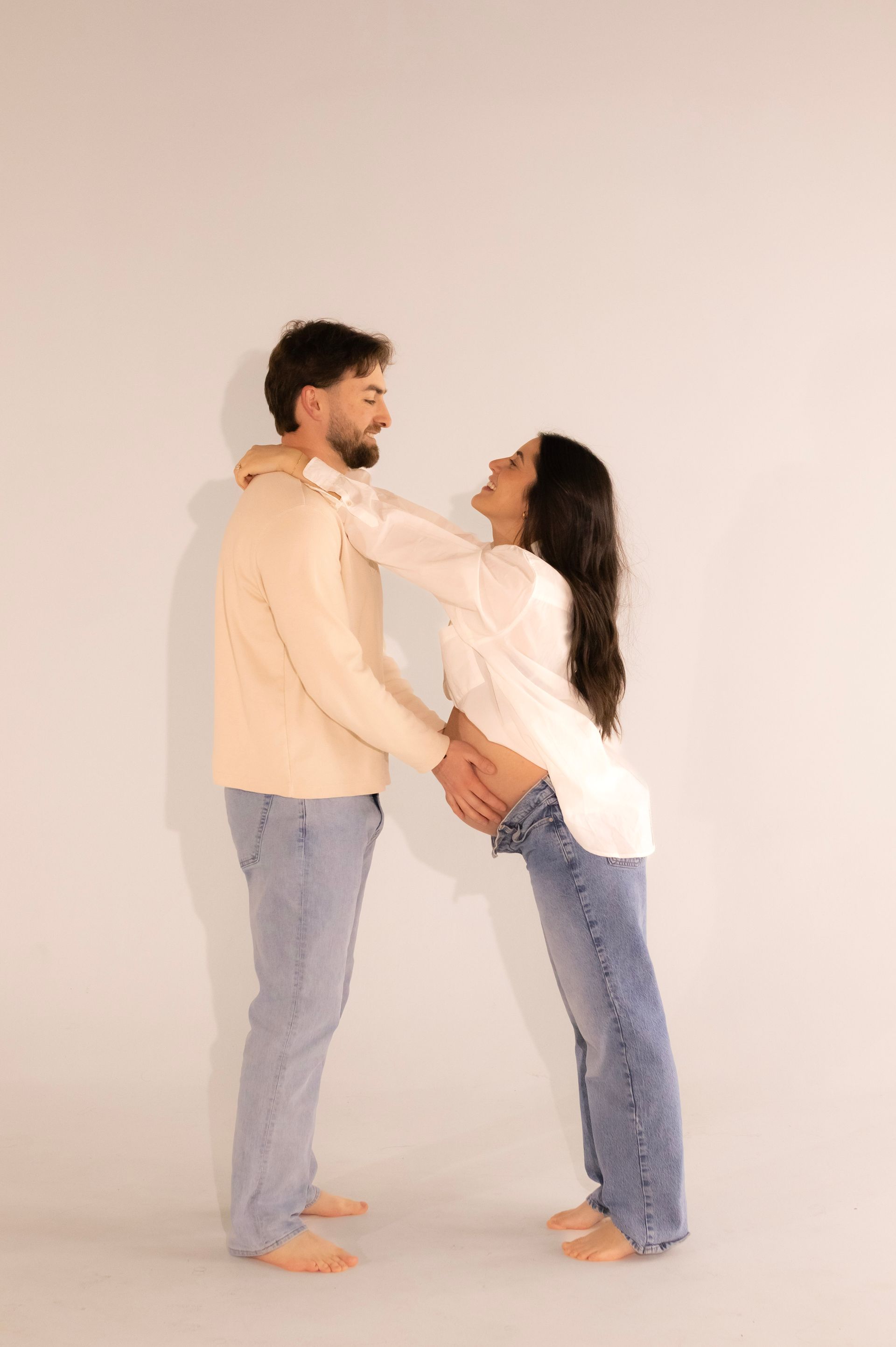 A man and a pregnant woman are standing next to each other holding hands.