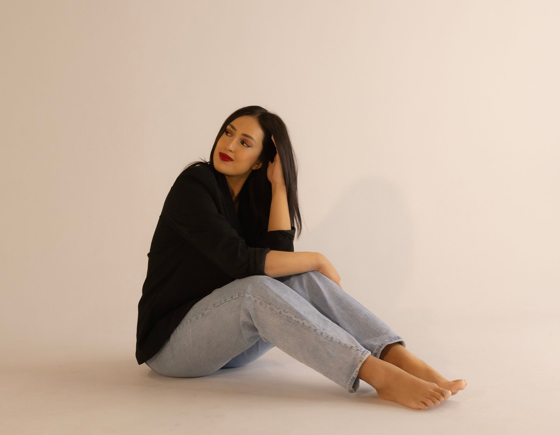 A woman is sitting on the floor with her legs crossed.