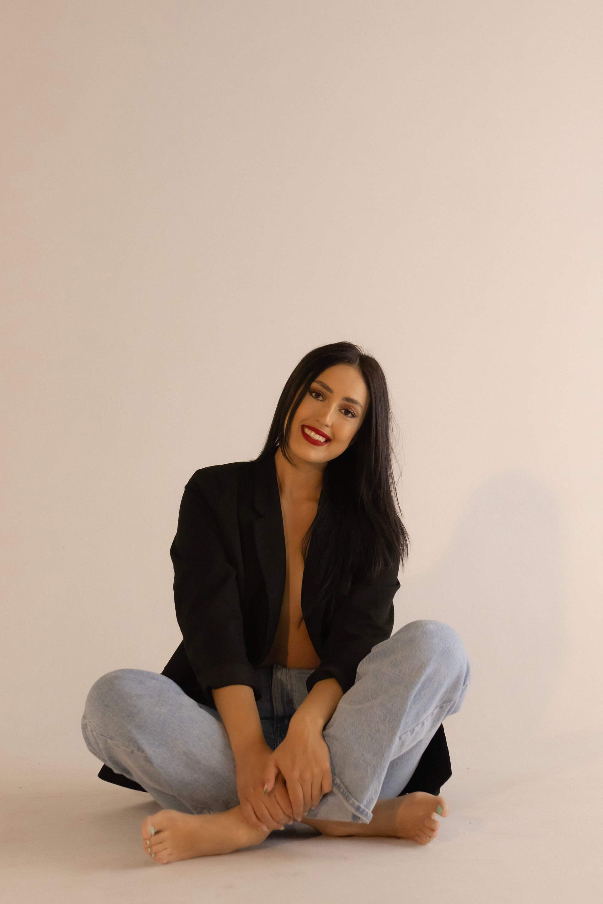 A woman is sitting on the floor with her legs crossed.