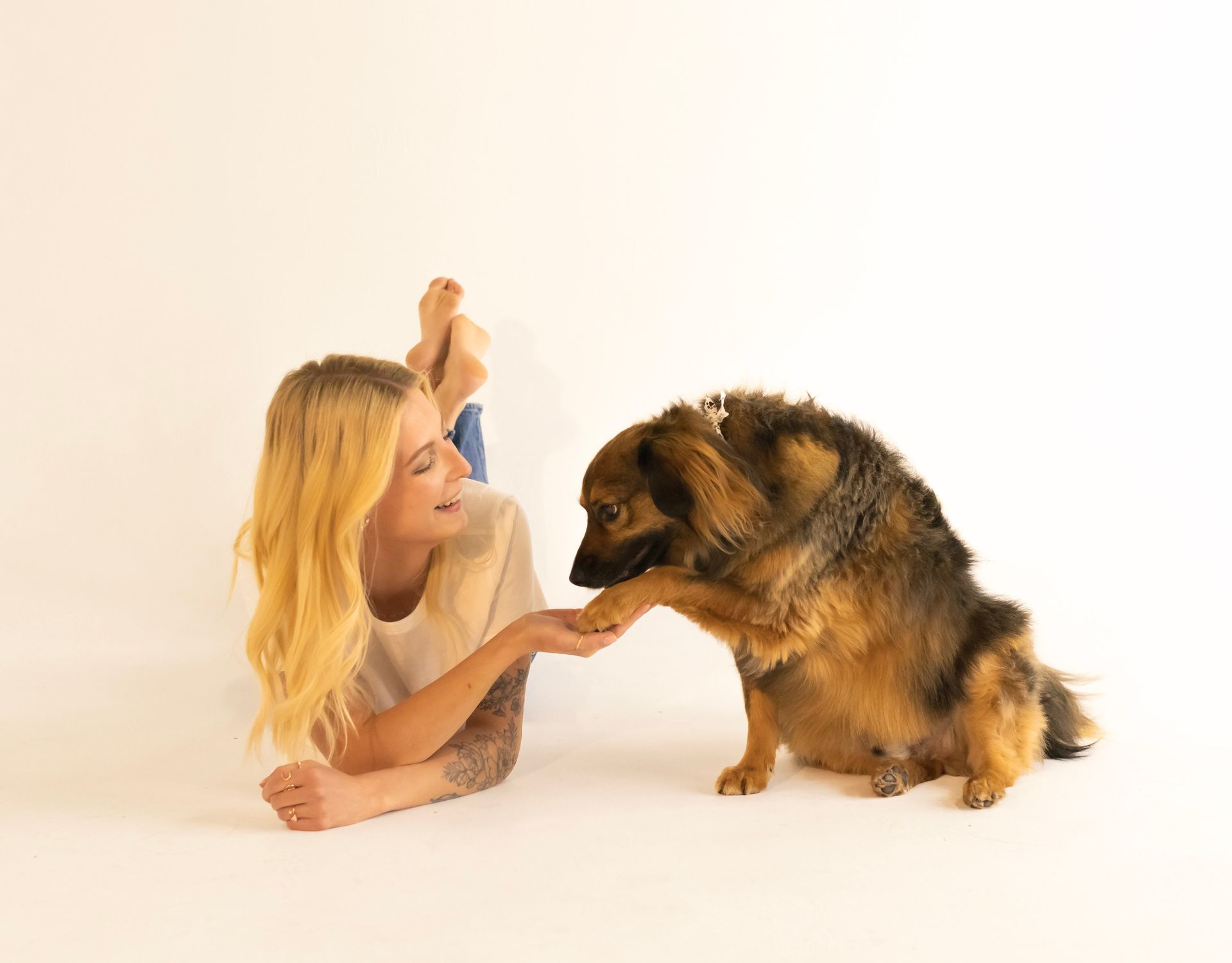 A woman is laying on the floor petting a german shepherd dog.