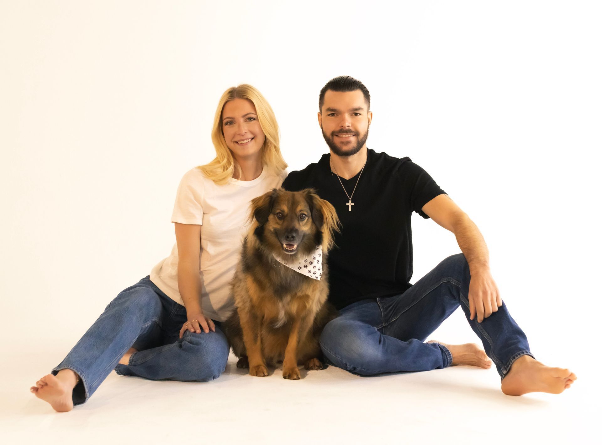 A man and a woman are sitting on the floor with a dog.