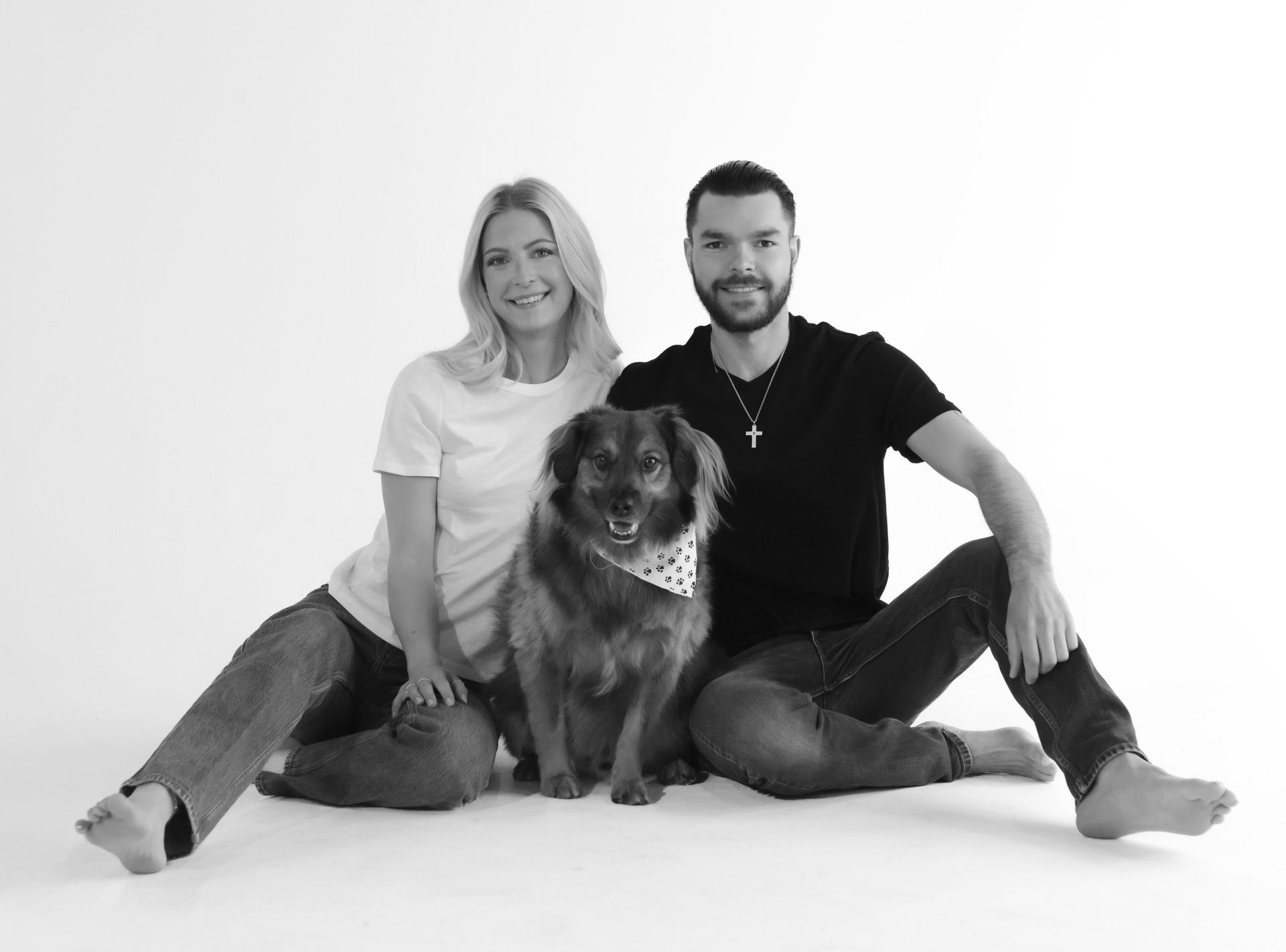 A man and a woman are sitting on the floor with a dog.