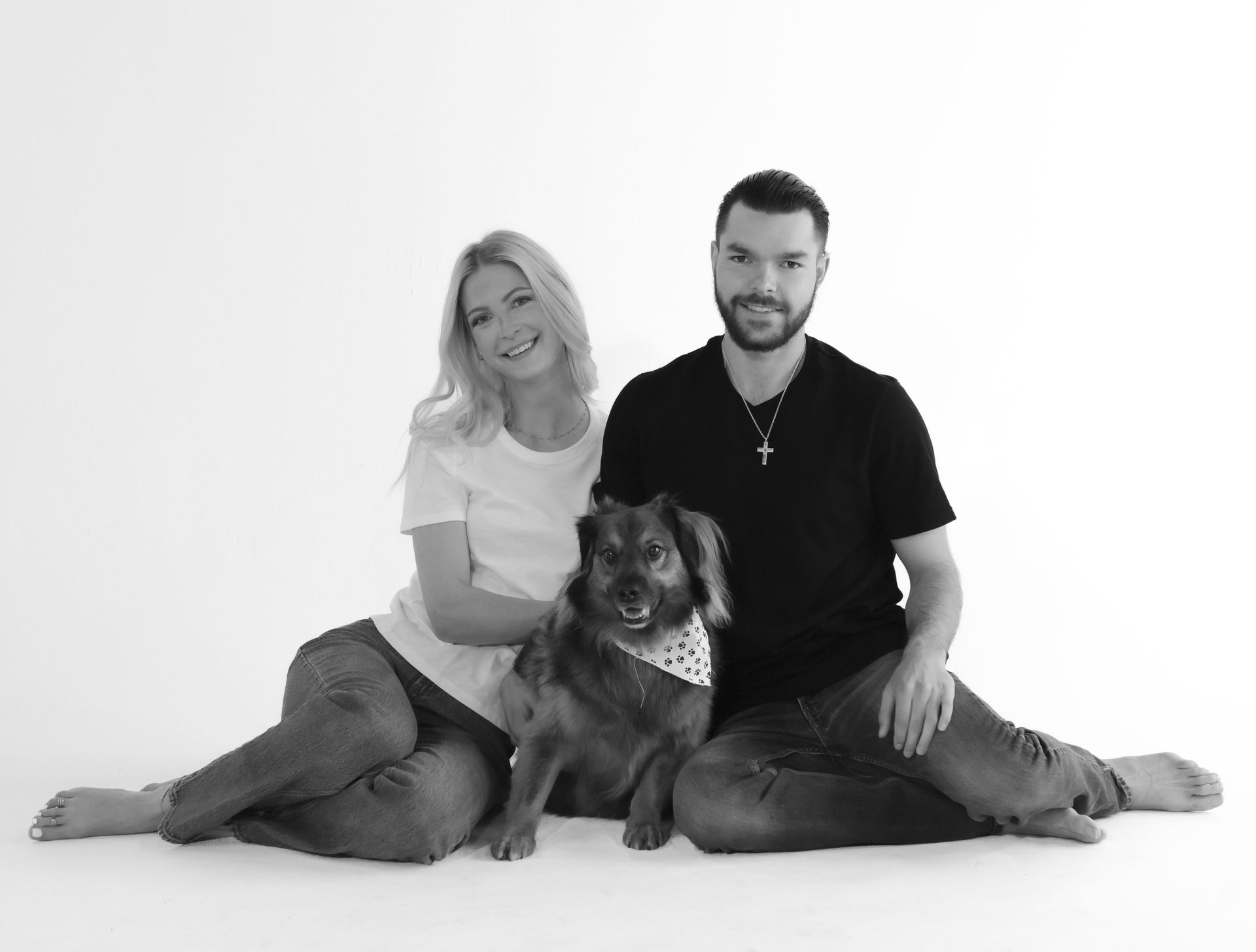 A man and a woman are sitting on the floor with a dog.