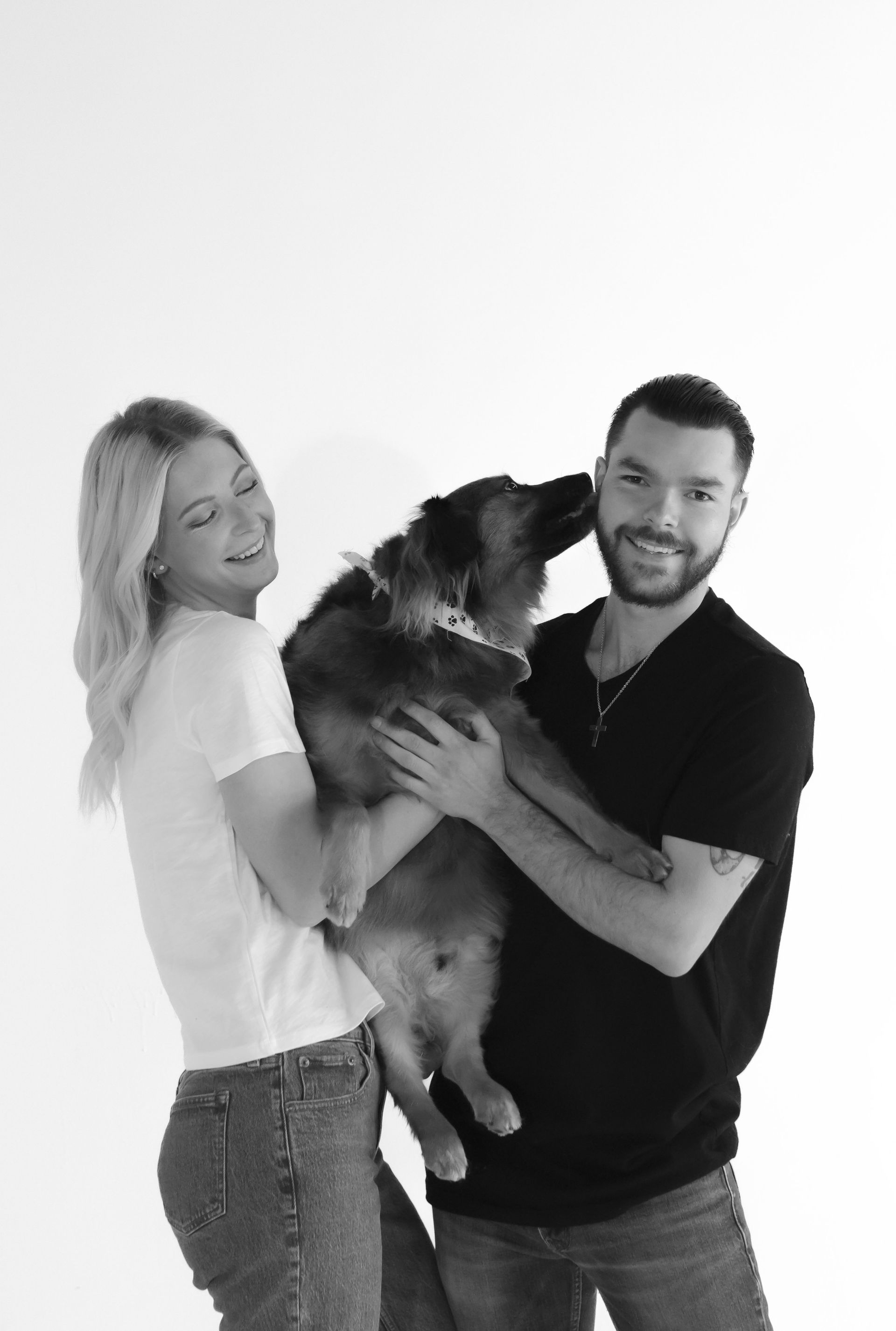 A man and a woman are holding a dog in their arms.