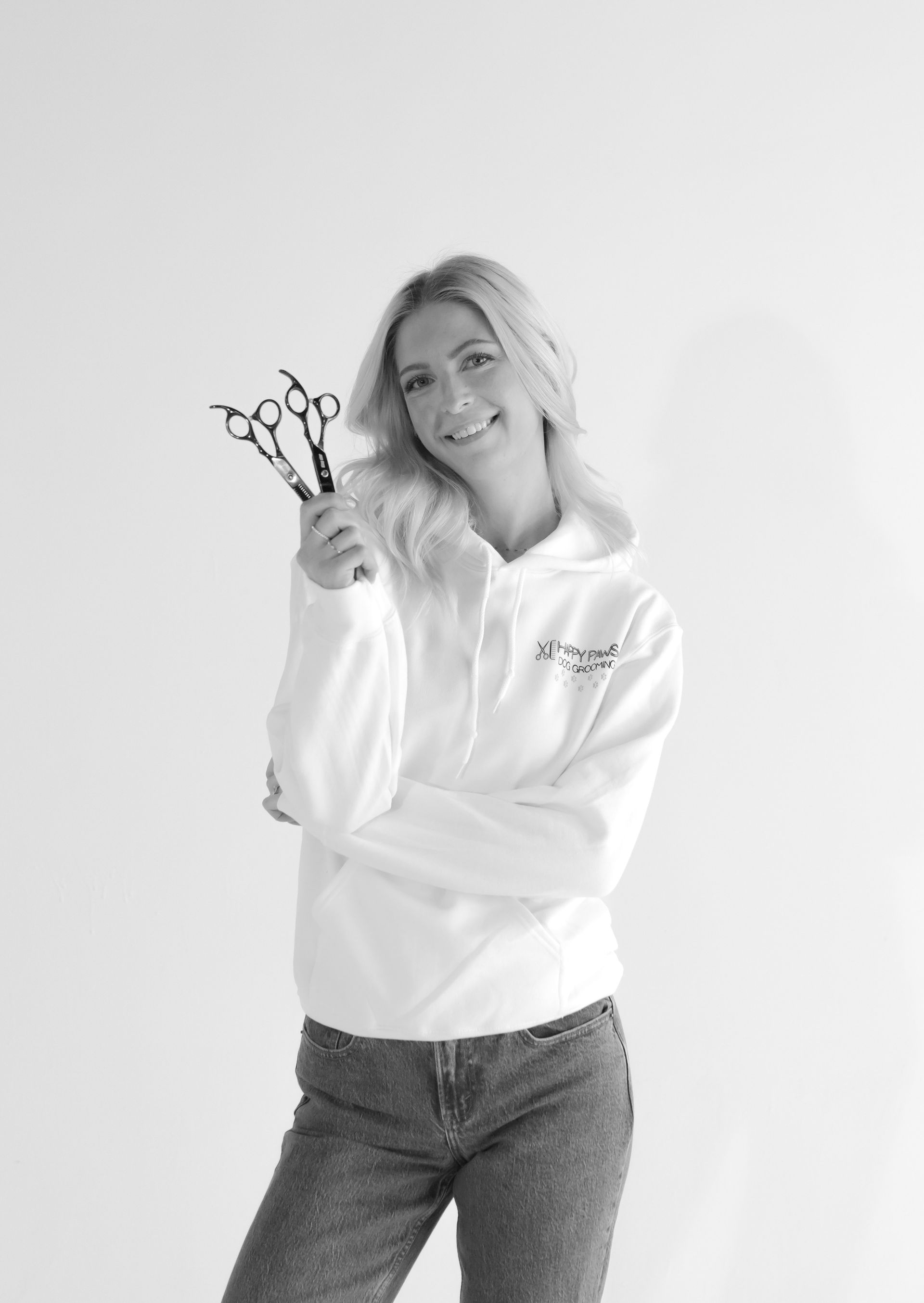 A woman in a white hoodie is holding a pair of scissors.