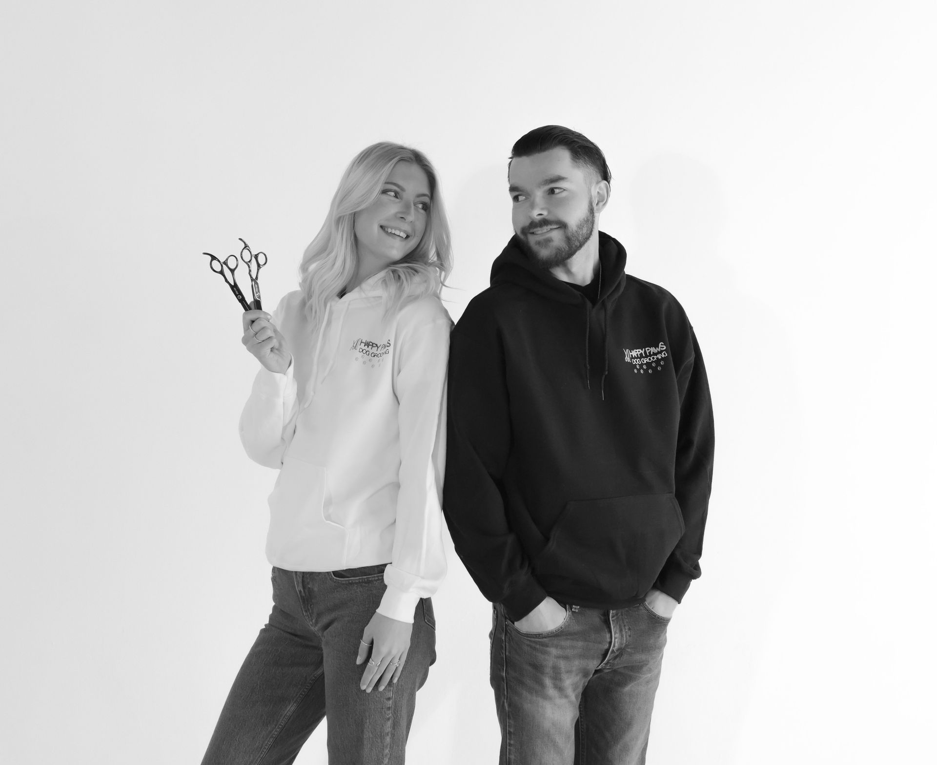 A man and a woman are standing next to each other . the woman is holding a pair of scissors.