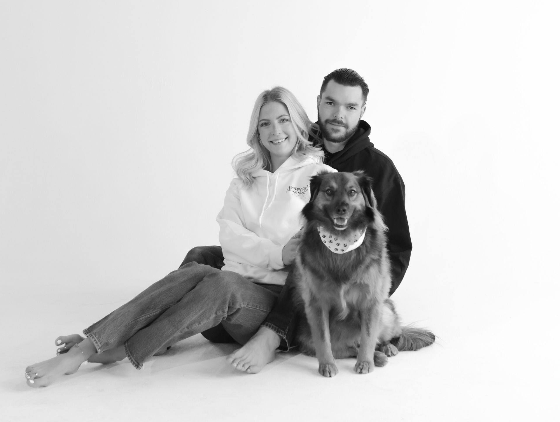 A man and a woman are sitting on the floor with a dog.