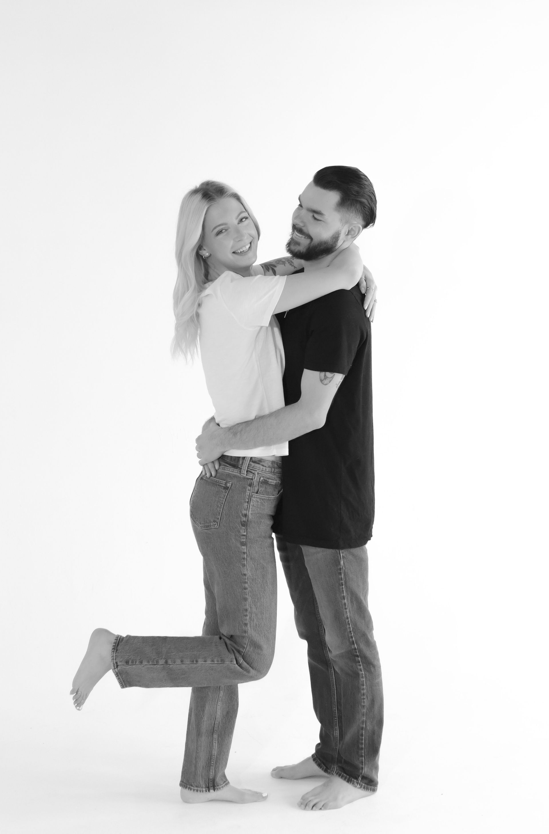 A man is holding a woman in his arms in a black and white photo.