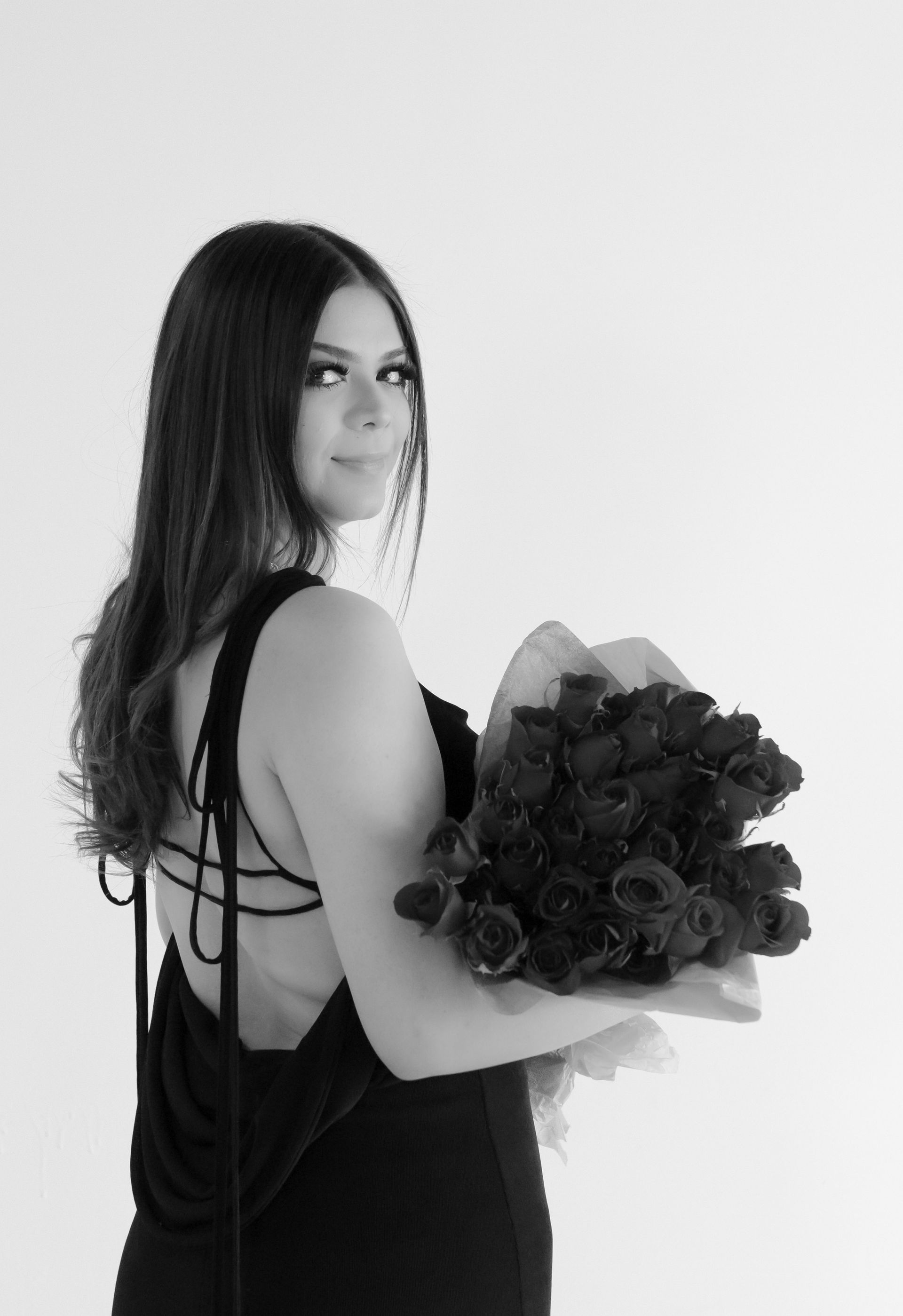 A woman in a black dress is holding a bouquet of flowers.