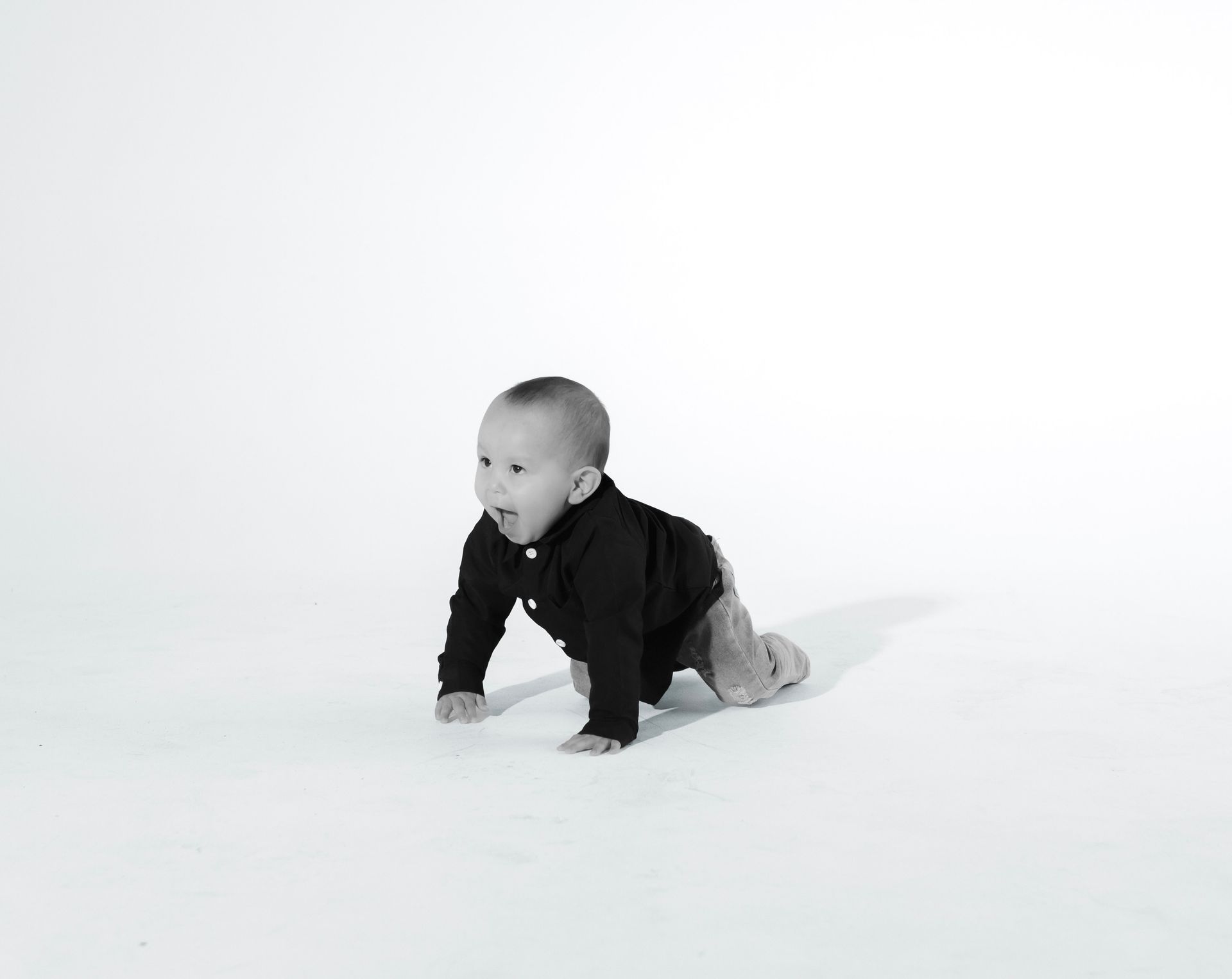 A baby is crawling on the floor in a black and white photo.