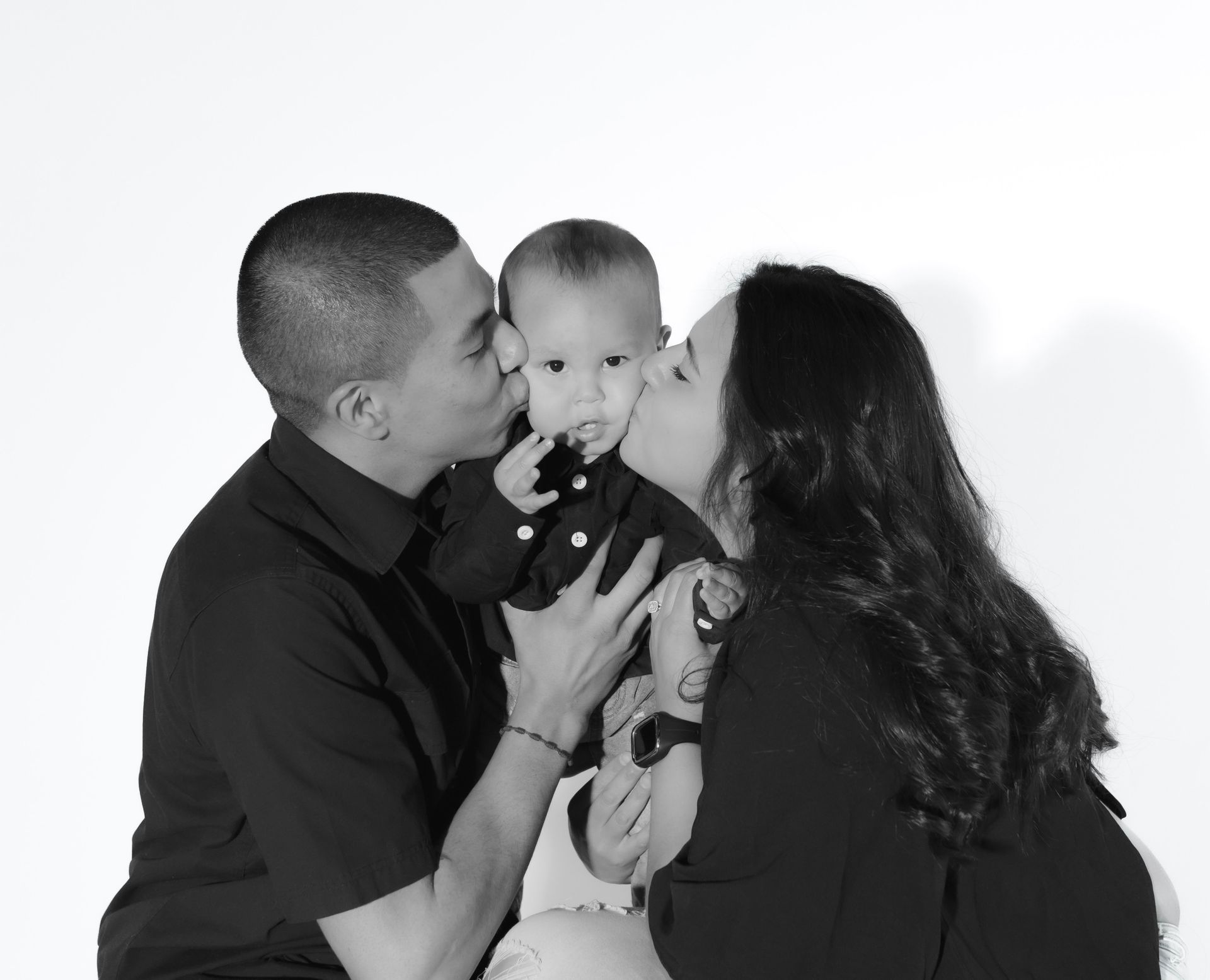 A man and woman kissing a baby on the cheek