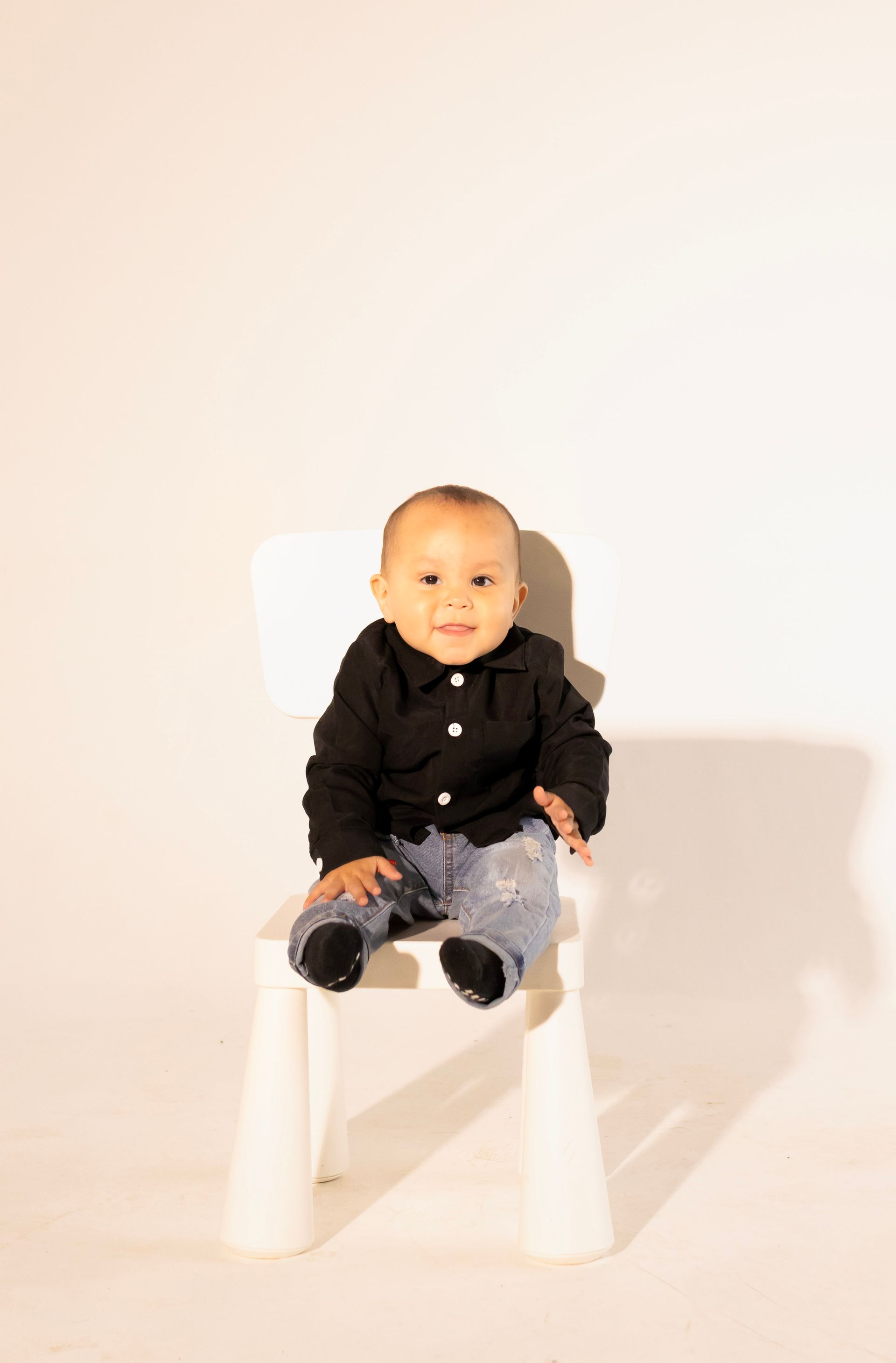 A baby is sitting on a white chair.