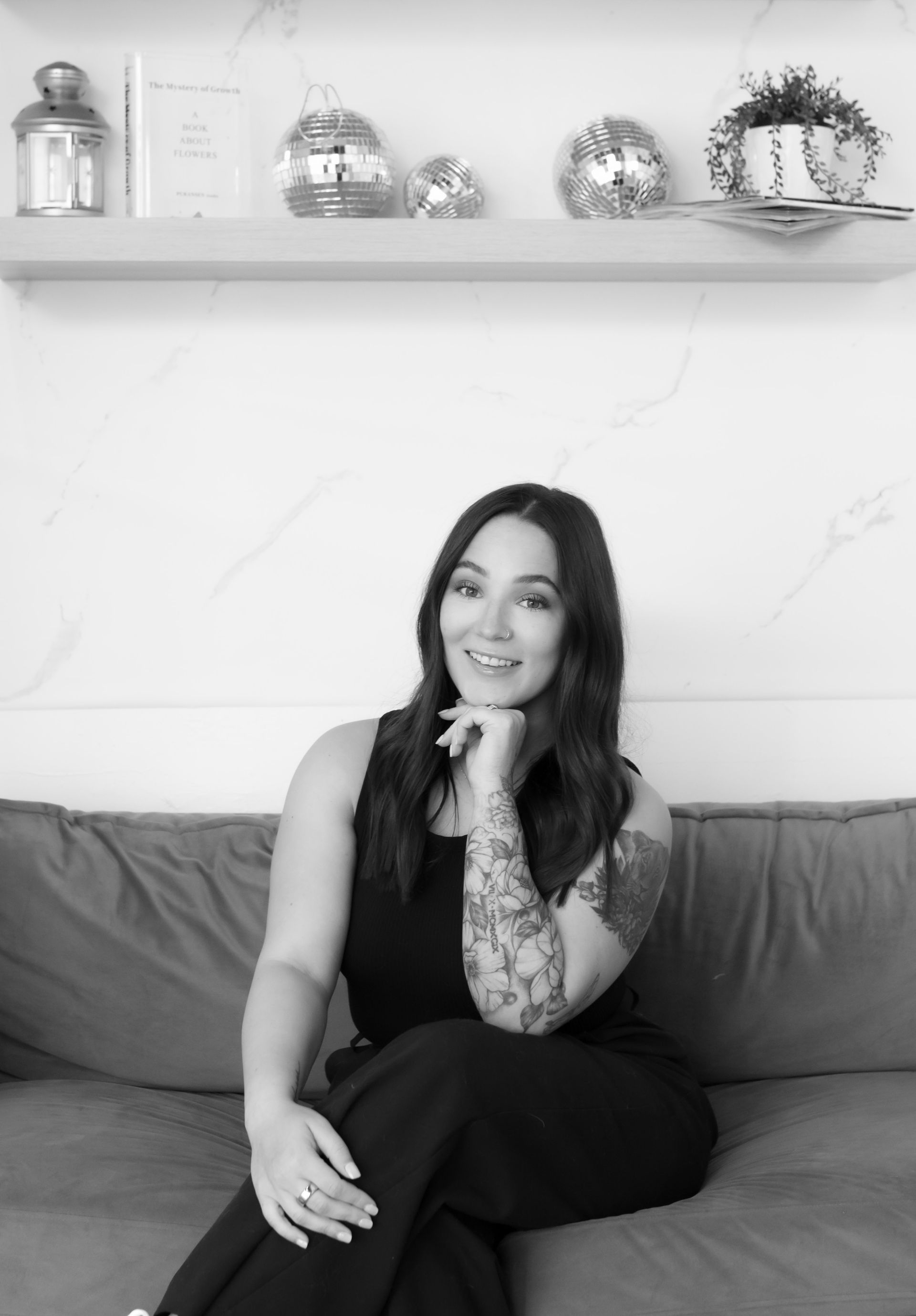 A woman is sitting on a couch with her hand on her chin.
