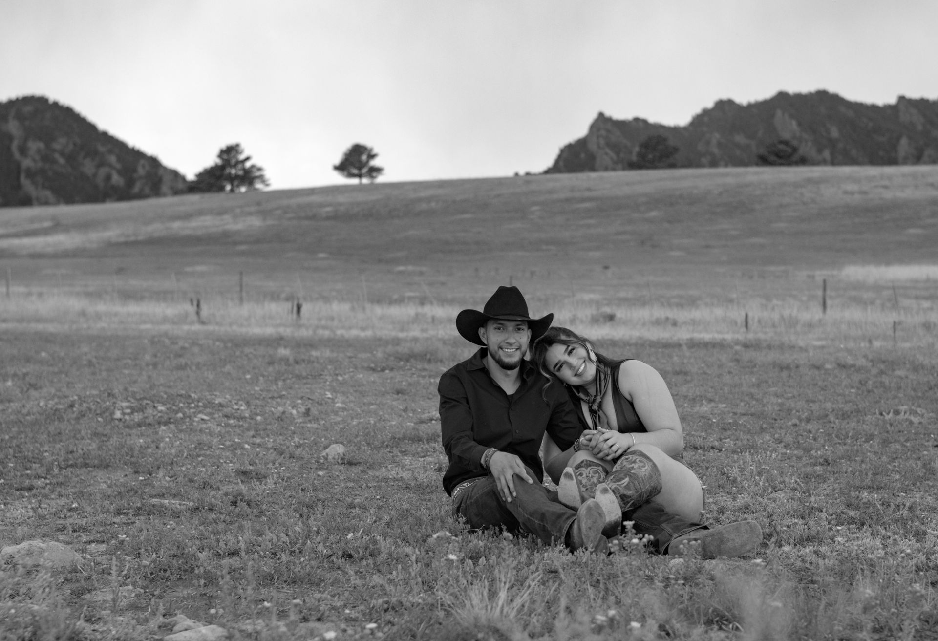 A black and white photo of a man and woman sitting in a field.