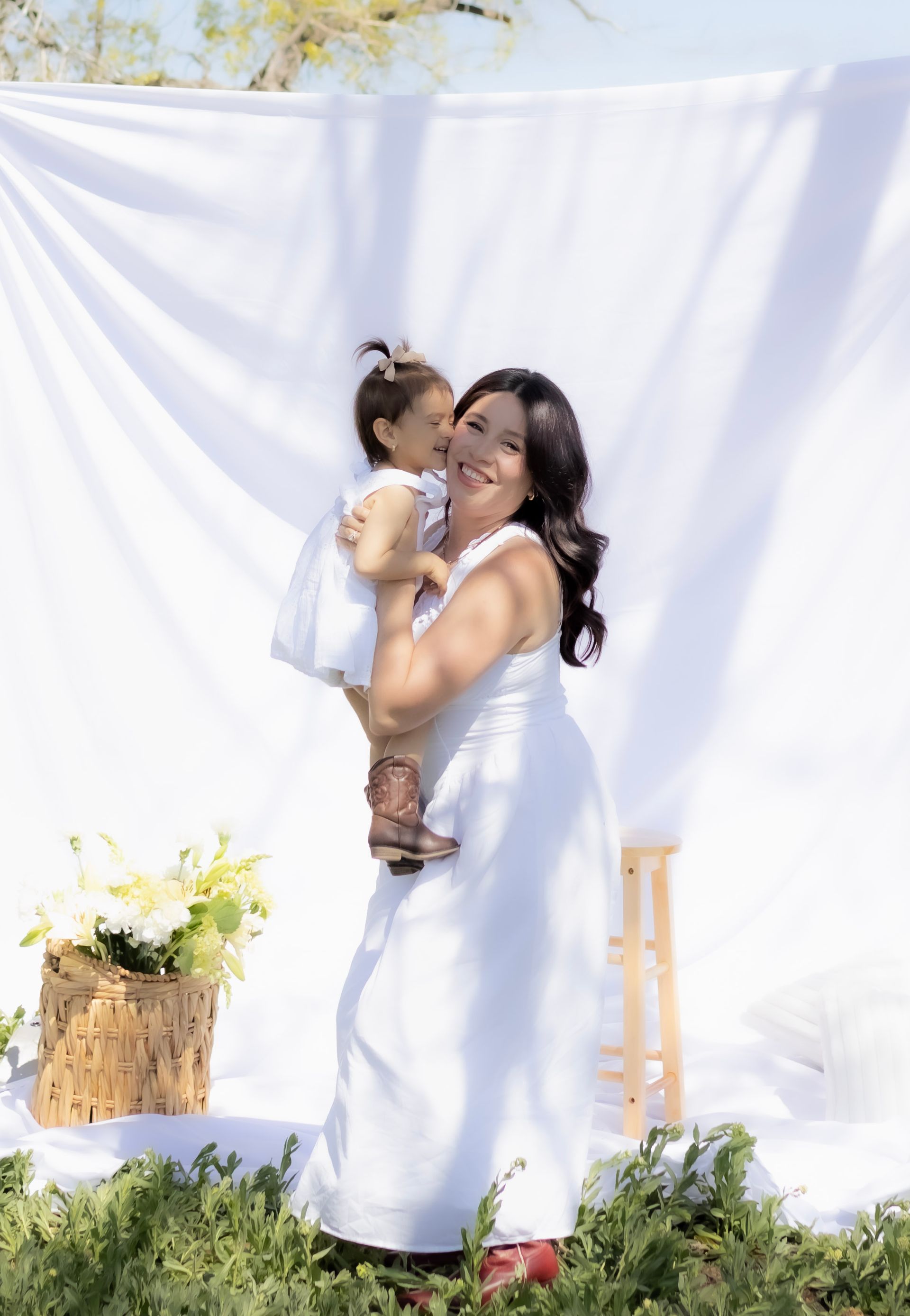 A woman in a white dress is holding a little girl in her arms.