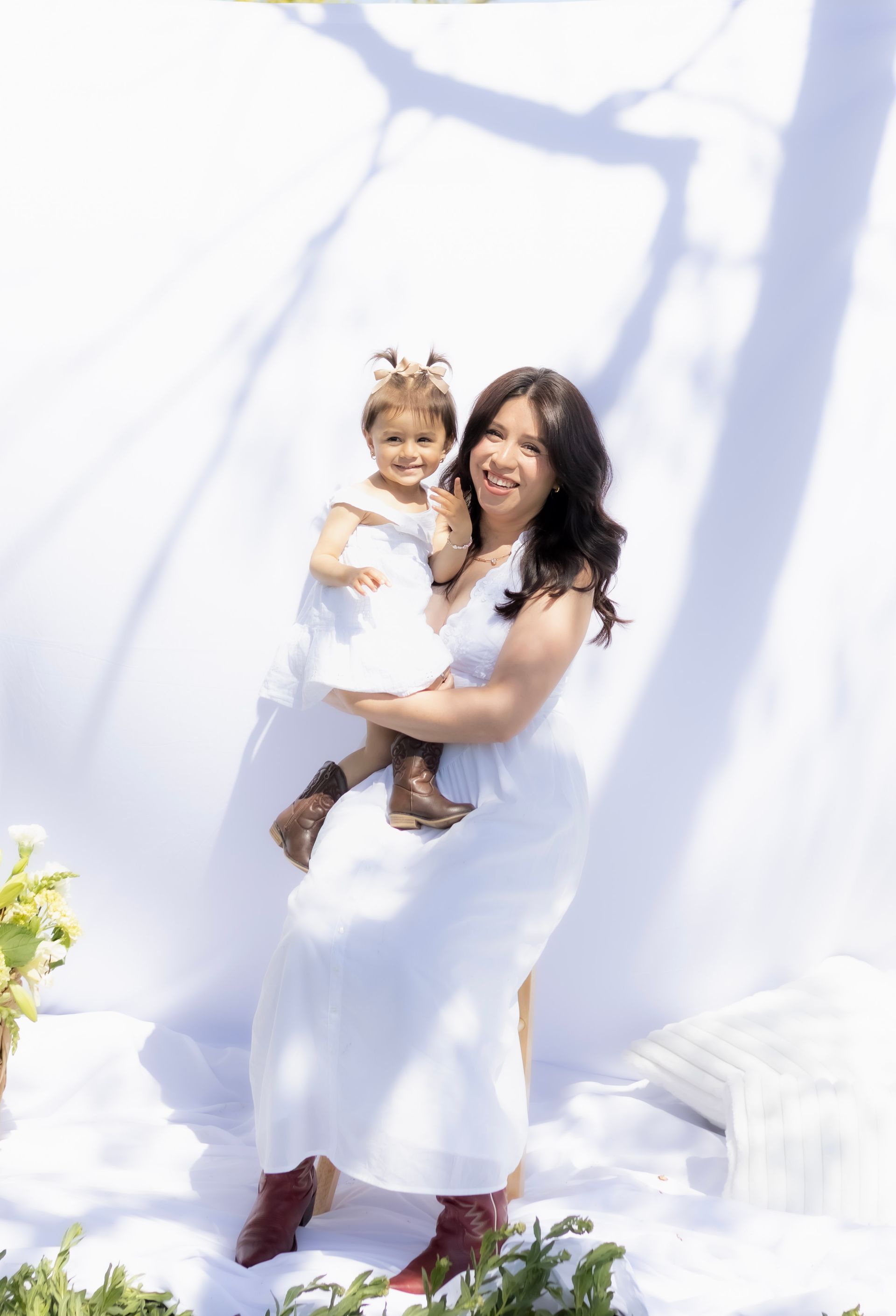 A woman in a white dress is holding a little girl in her arms.