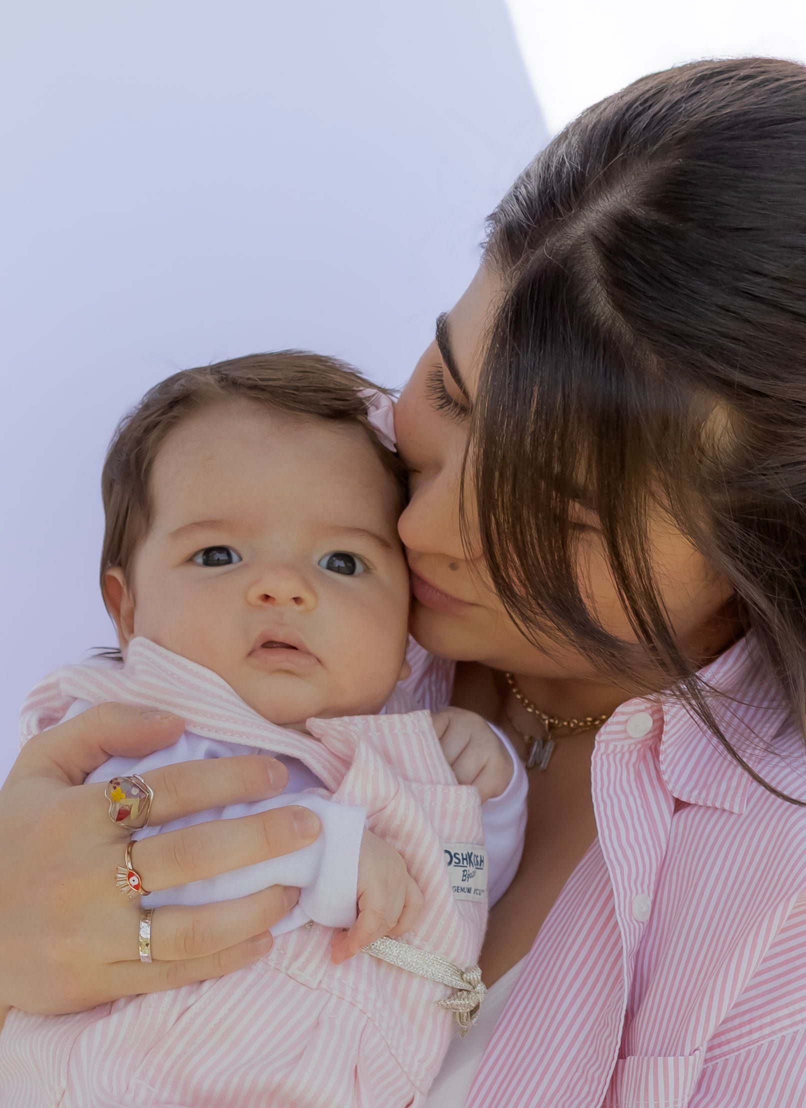 A woman is kissing a baby on the cheek.
