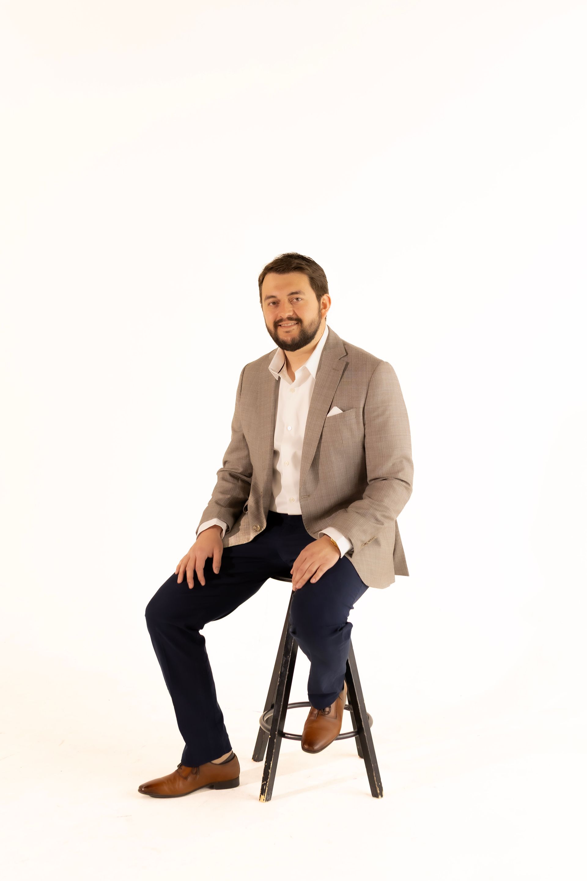A man in a suit is sitting on a stool.