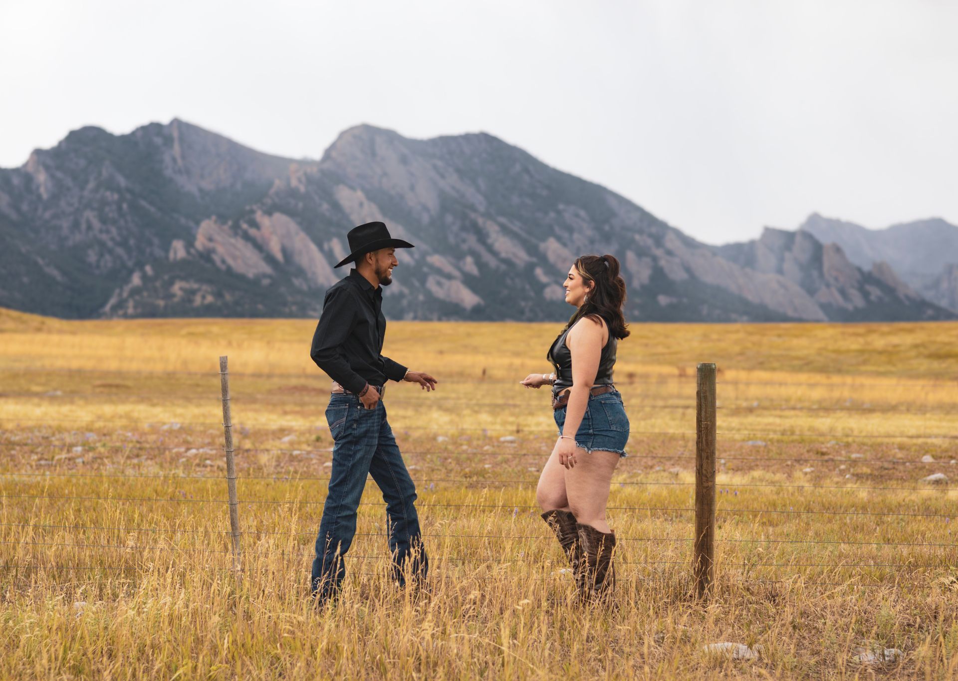 A man and a woman are standing in a field talking to each other.