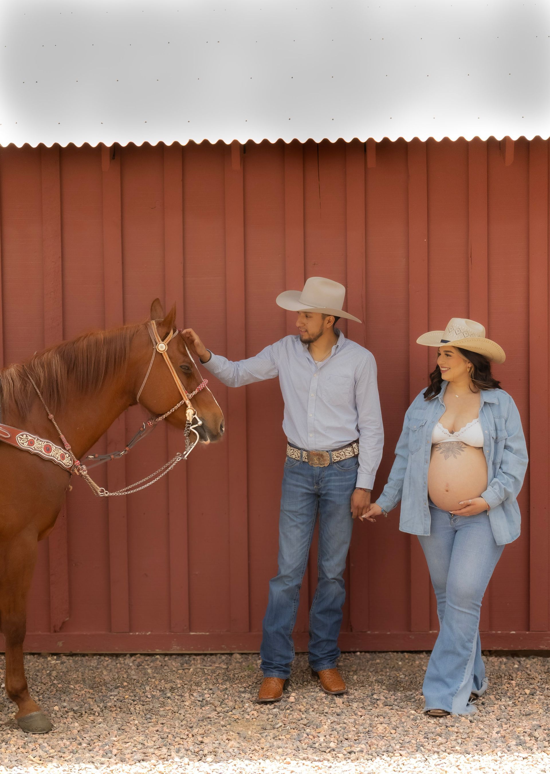A man and a pregnant woman are standing next to a horse.